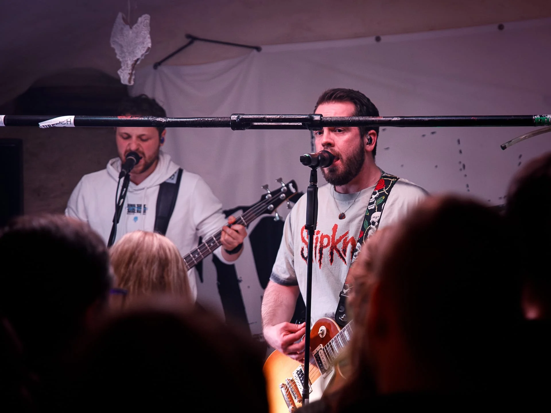 Musicians performing live on stage at a concert, with audience members in the foreground.