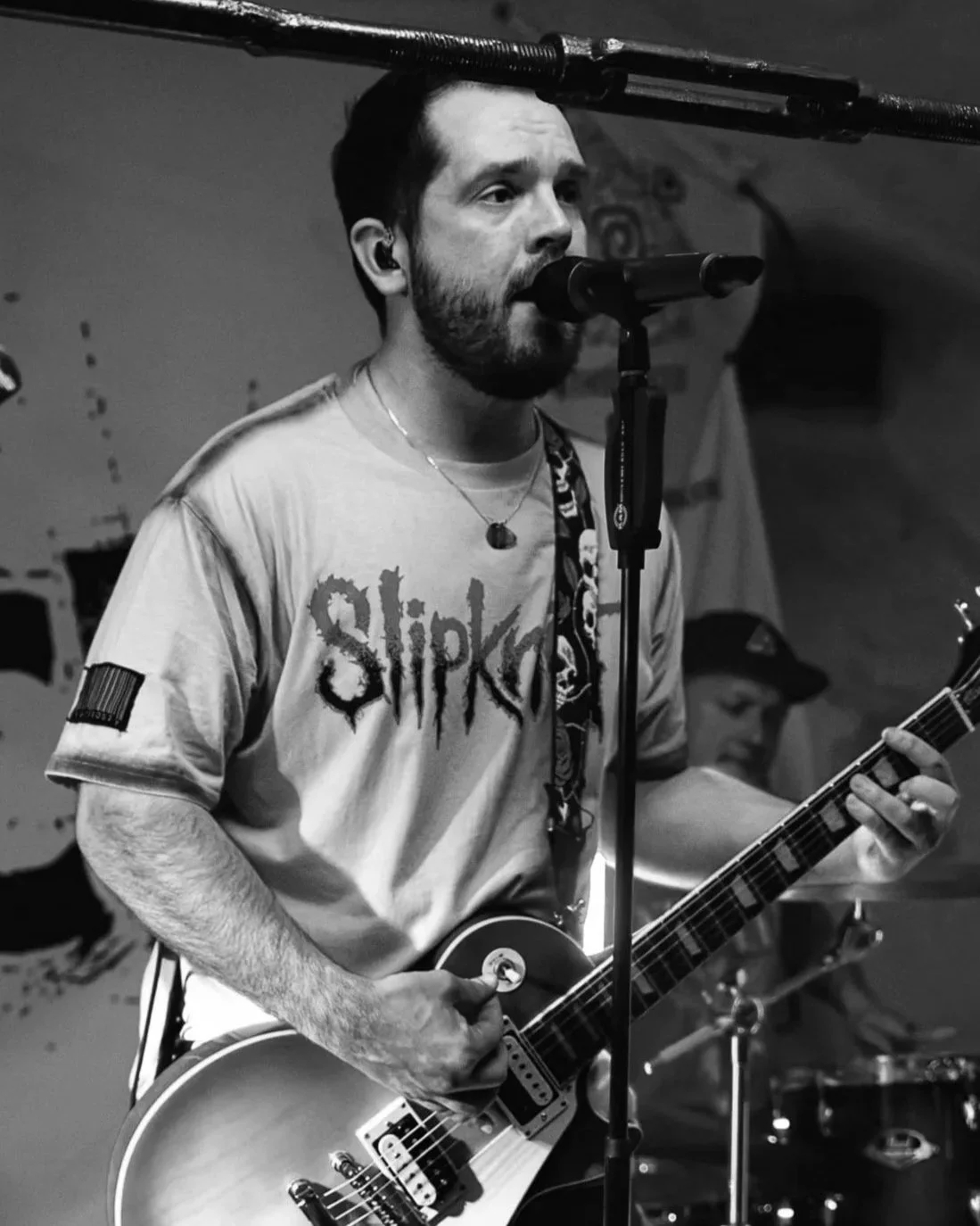 Niklas spielt Gitarre und singt in einem Aufnahmestudio, trägt ein Slipknot T-Shirt, schwarze Haare und einen Bart.