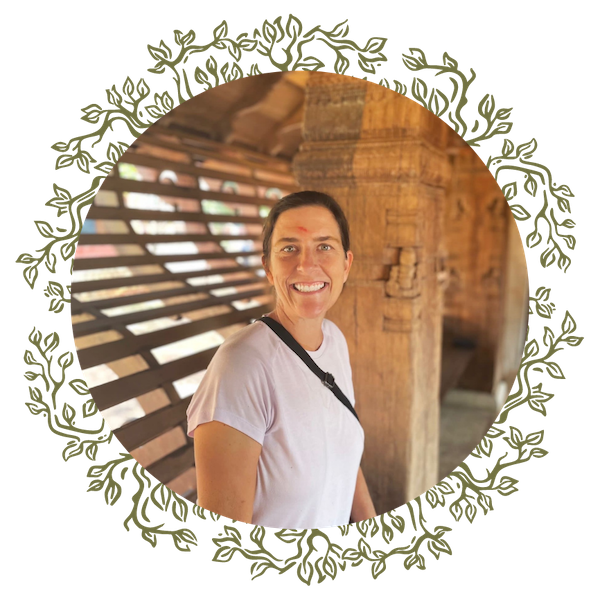 Woman smiling in a white t-shirt inside a wooden structure with beams and large wooden columns.