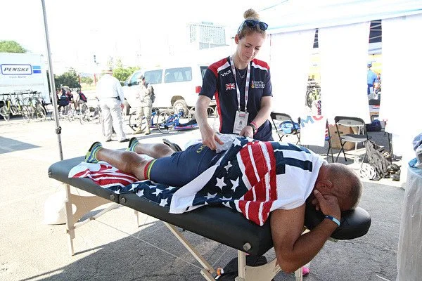 Sally Lygo providing sports physiotherapy treatment at an outdoor sporting event.