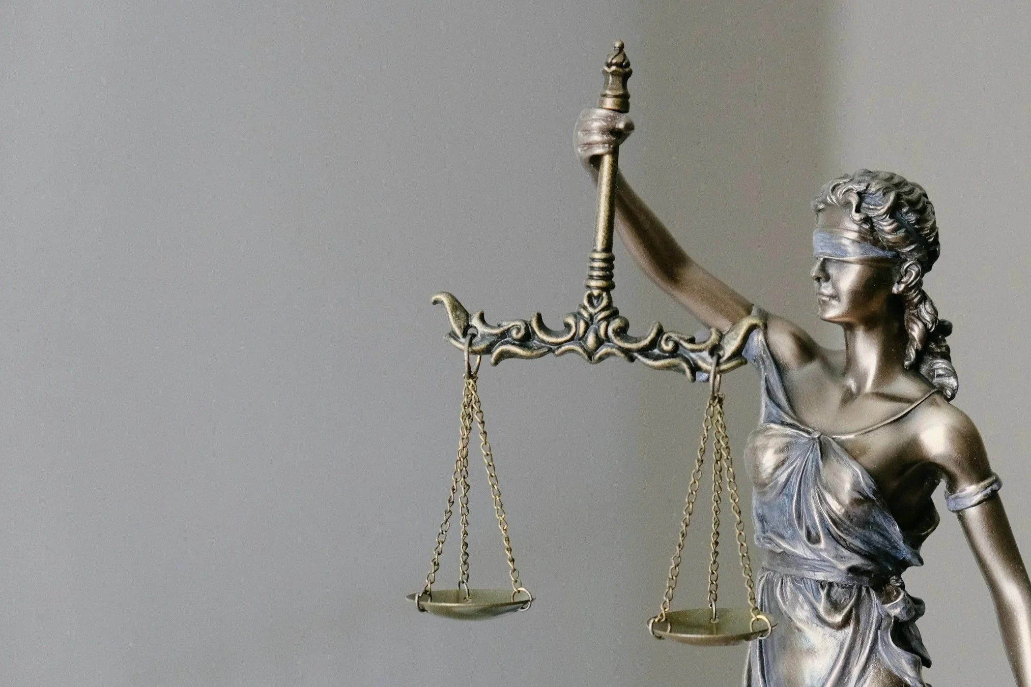 Statue of Lady Justice with a blindfold, holding a balance scale and a sword, representing fairness and the legal system.