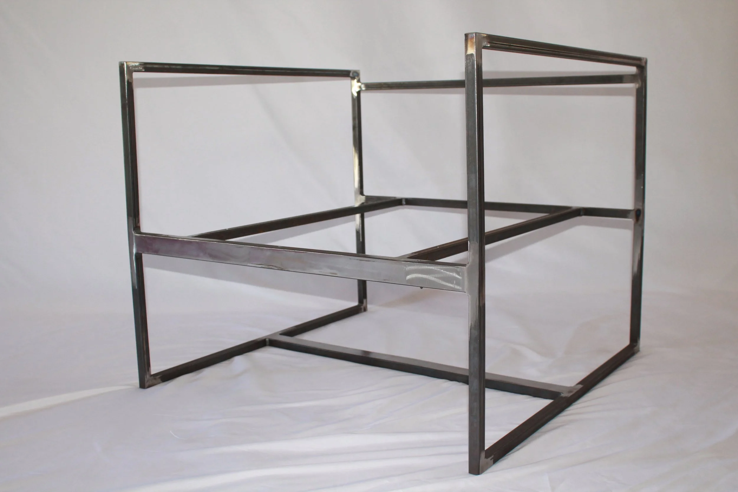 A metal rectangular frame structure with open sides, standing on a plain white surface against a white background.