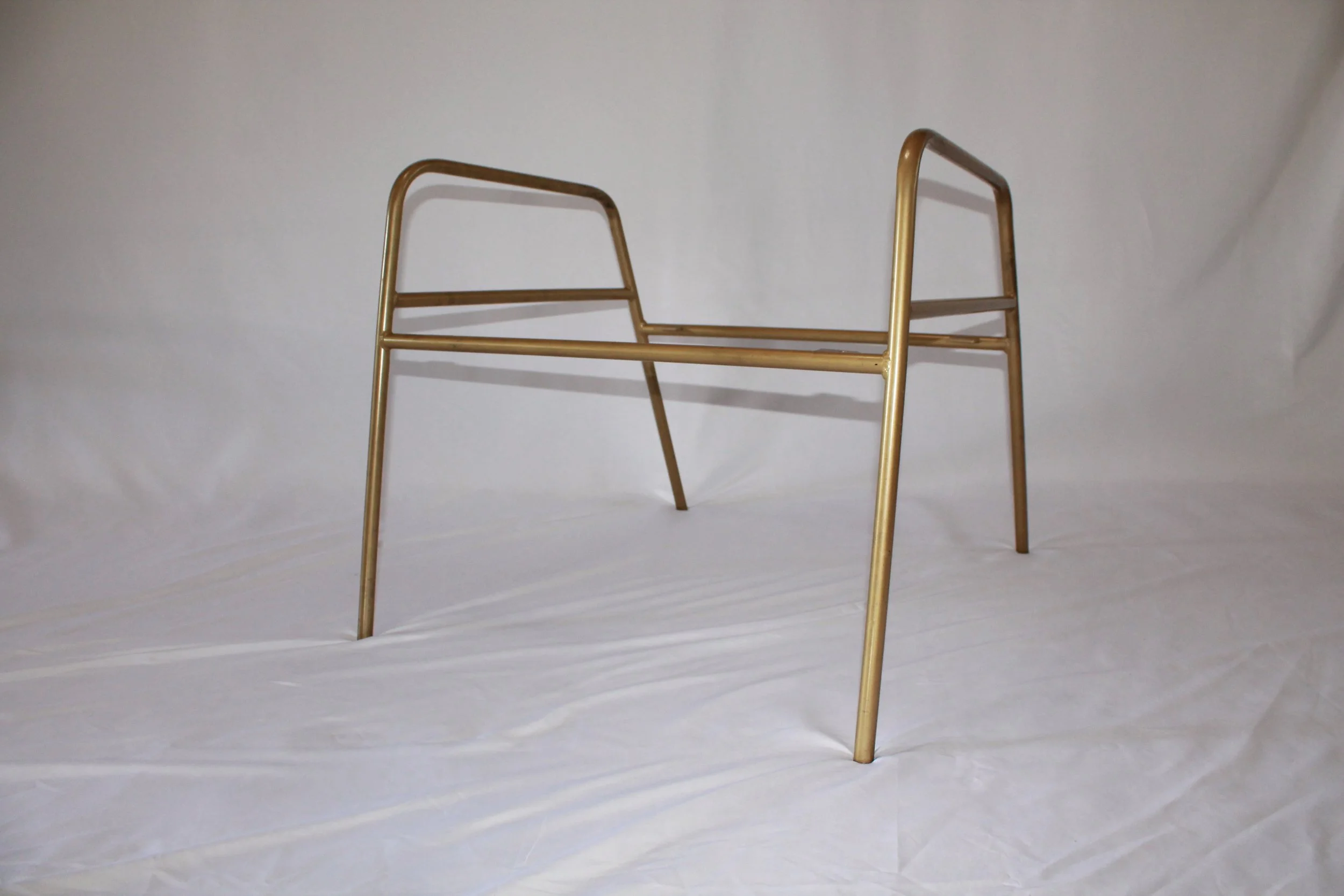 A set of four gold-colored metal chair legs and frames standing upright on a plain white background.