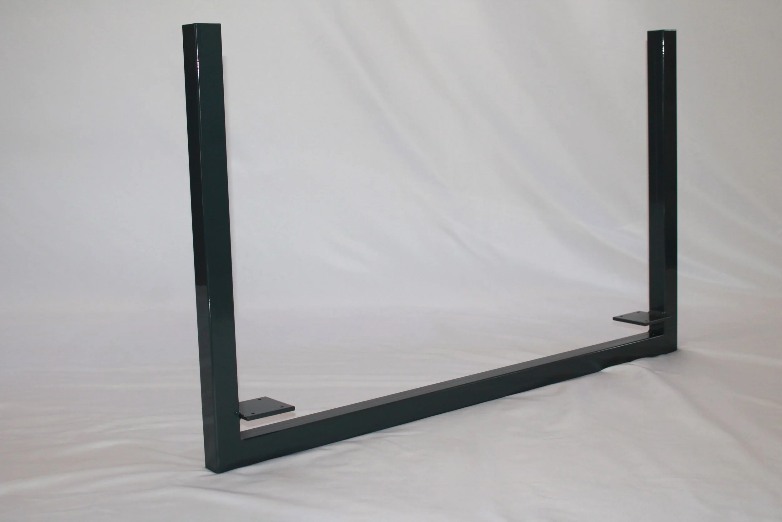 A black metal bed frame with rectangular posts and a base, placed on a white surface against a plain white background.