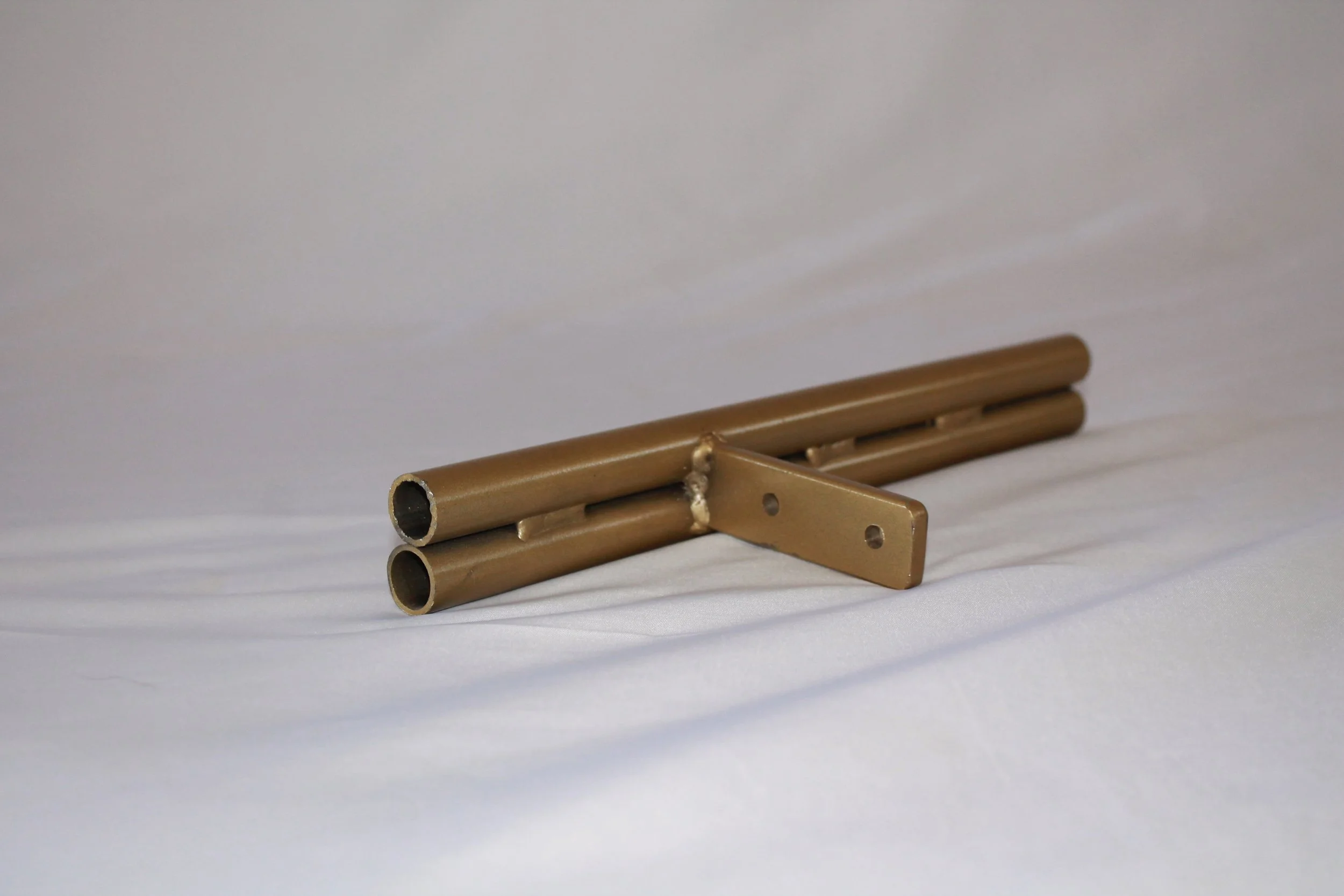 A set of beige metal pipes and a metal bracket arranged on a flat white surface.