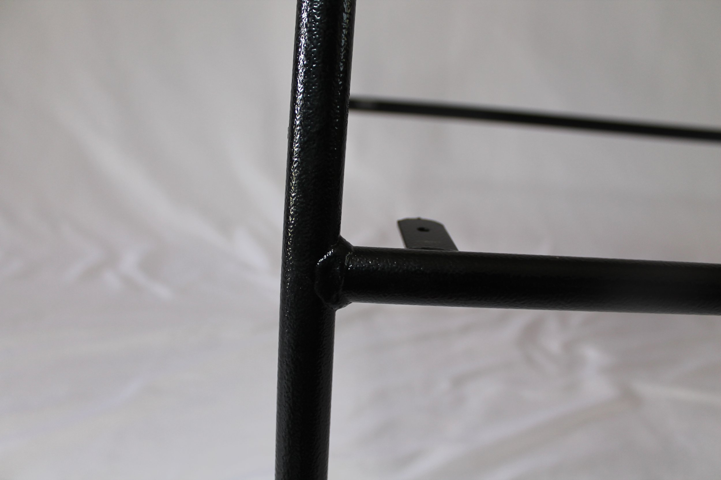 Close-up of a black metal chair leg with a textured surface, against a plain light background.