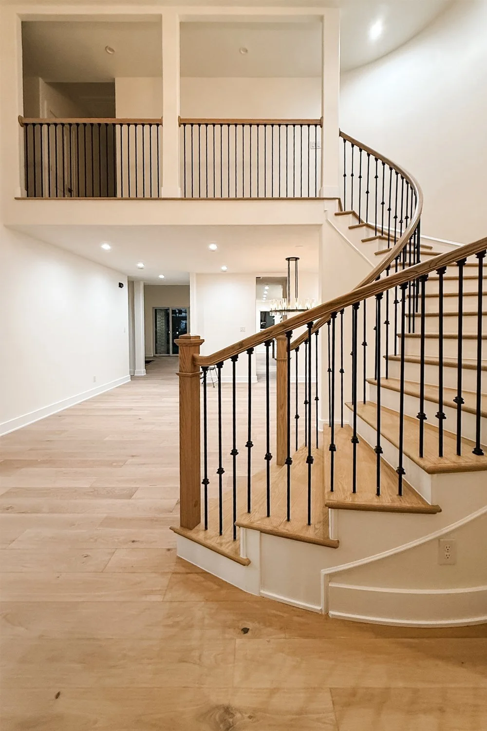 A completely remodeled great room, featuring a curved staircase, simplified layout, and removal of two beams in the center of the space.