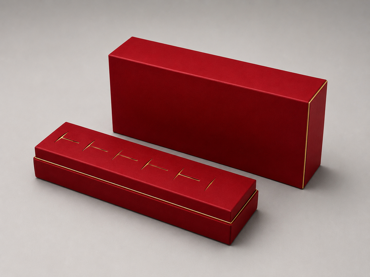 Two red rectangular boxes with gold accents, one open and one closed, on a gray surface.