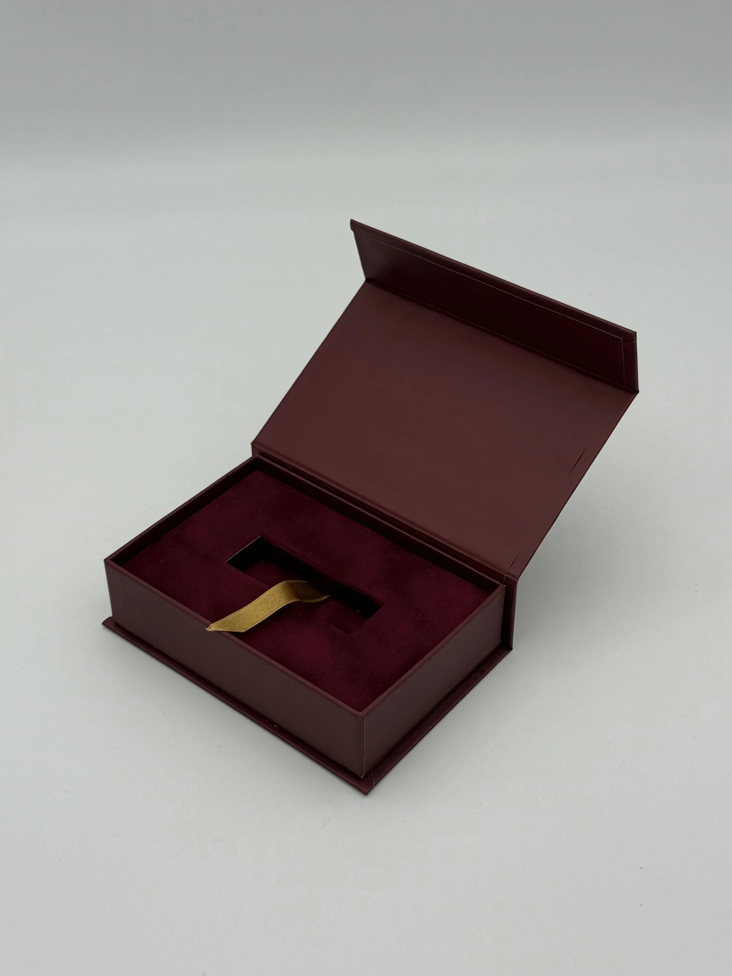 Open burgundy gift box with a yellow ribbon, empty inside, on a white surface.