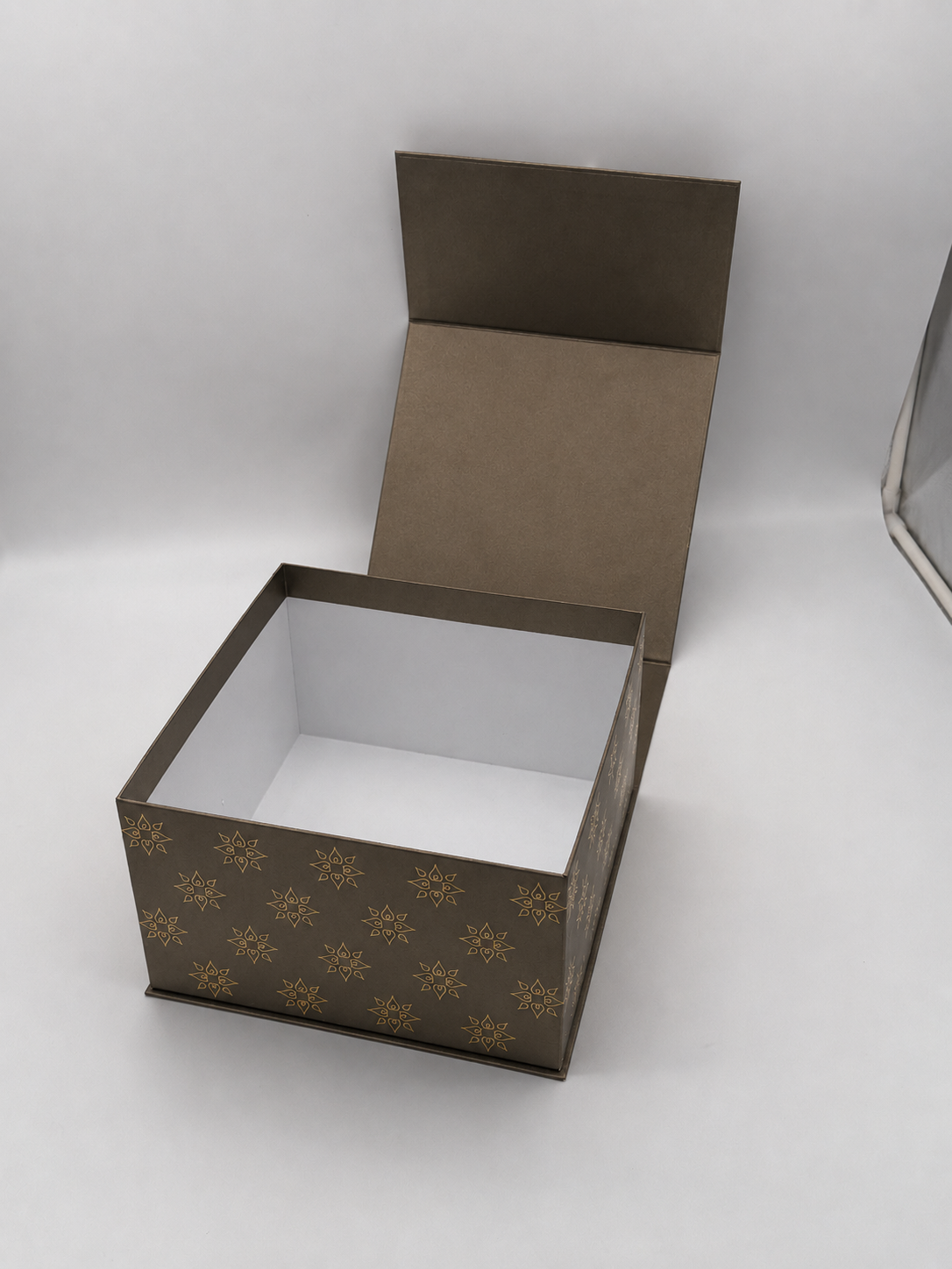 Empty decorative gift box with a patterned exterior and a hinged lid, placed on a white surface.