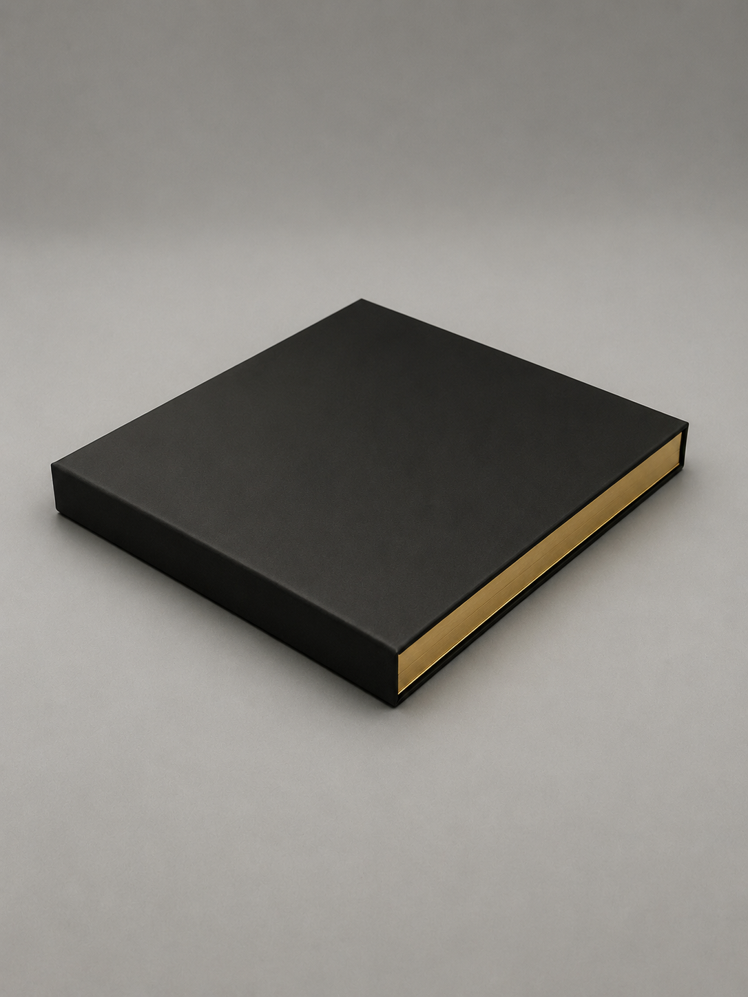 Black hardcover book with gold edges on a gray background