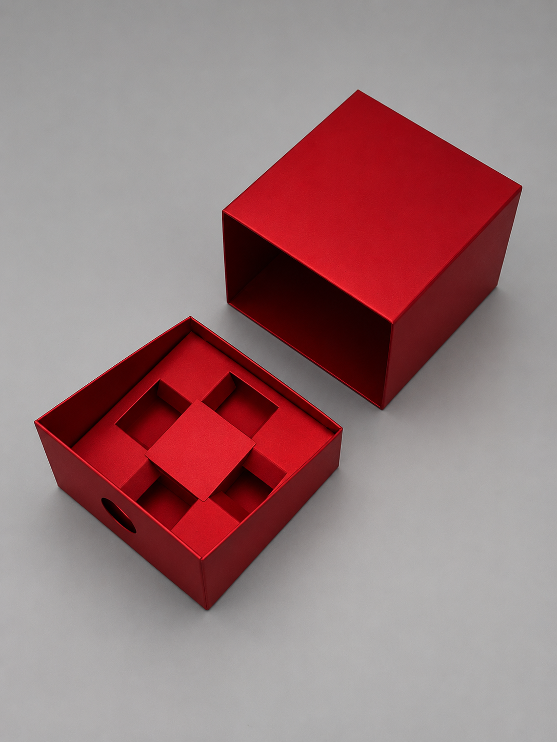 Red open box with inner compartments and removable tray placed on a gray surface.