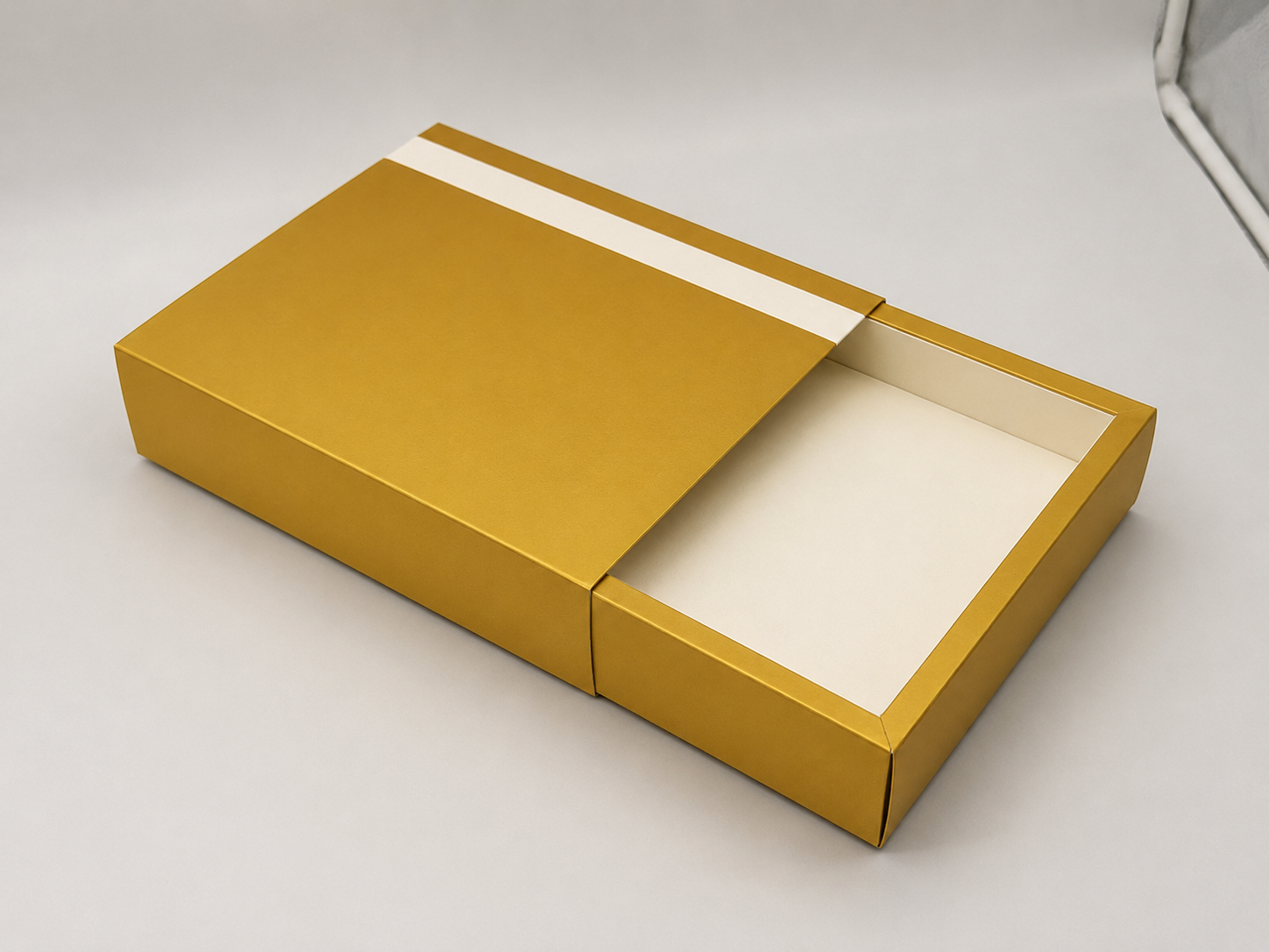 Open gold and white rectangular box on a white surface.
