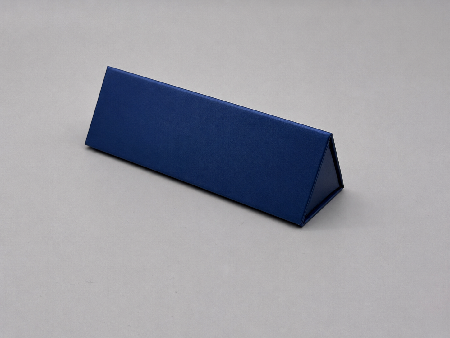 A blue, triangular prism-shaped object on a light gray background