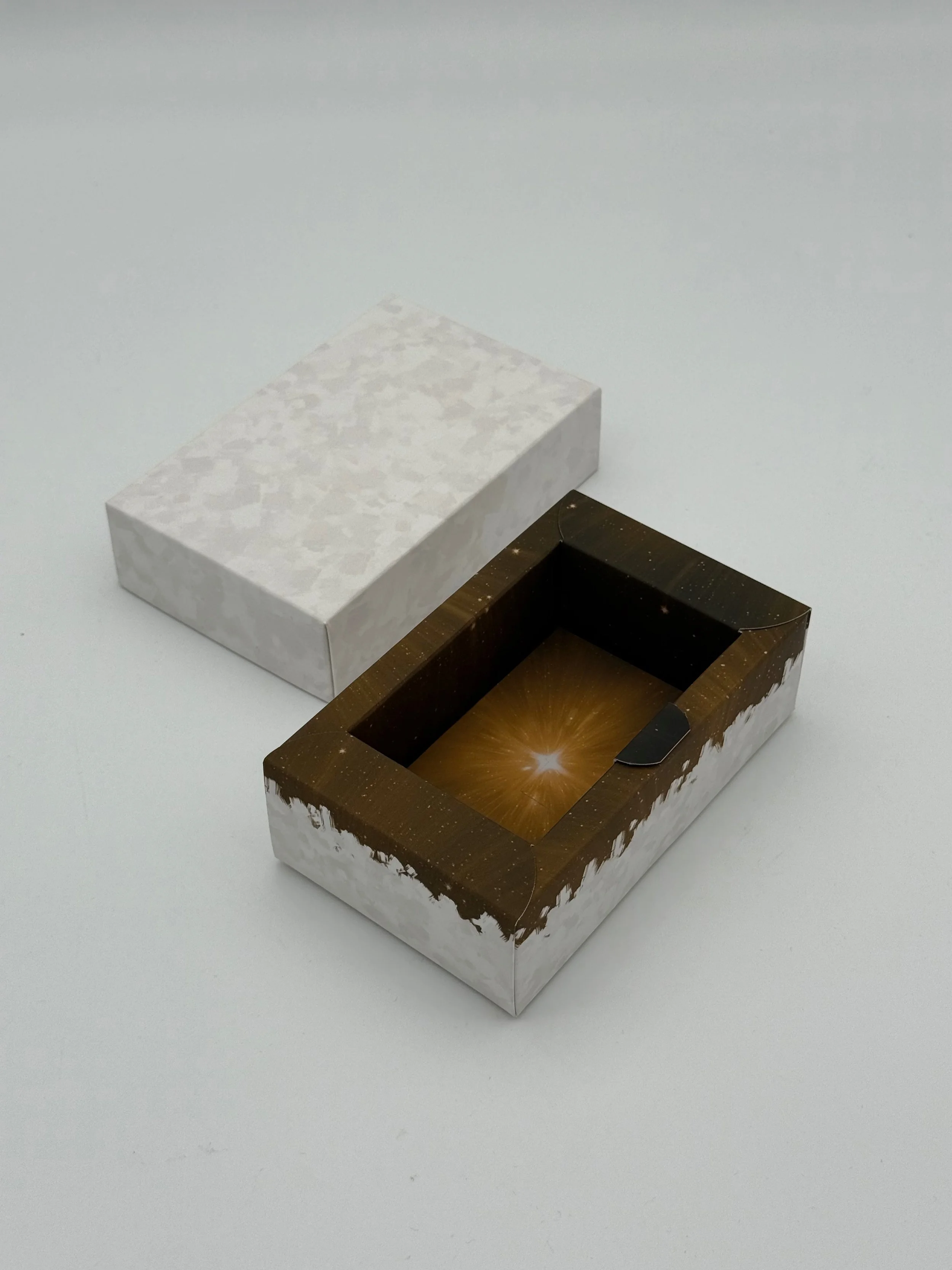 Two rectangular boxes with open tops, one with a galaxy design and the other with a marble pattern, placed on a white surface.