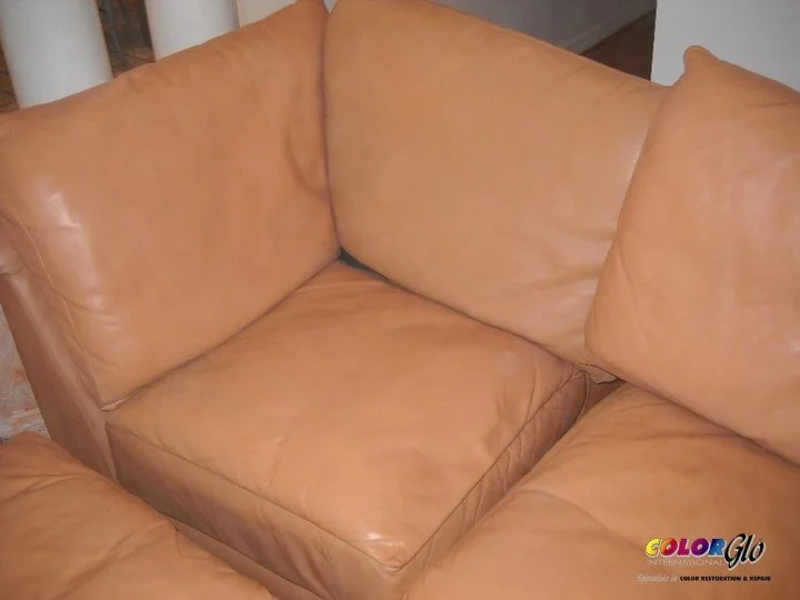Close-up of a tan leather couch with visible wear and creases.