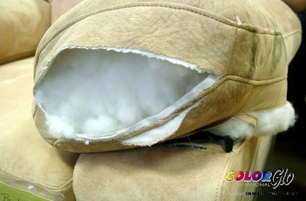 A beige armrest with a torn fabric cover revealing white stuffing inside.