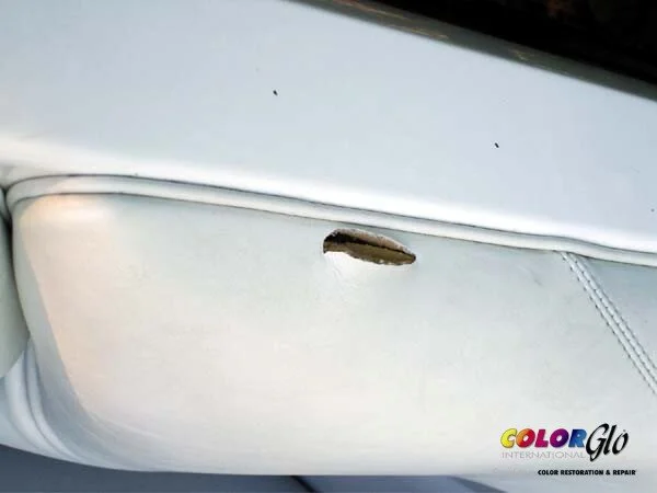 Close-up of white leather car seat with a tear and scratches, next to a logo that reads 'Color Glo International LLC' for color restoration and repair.