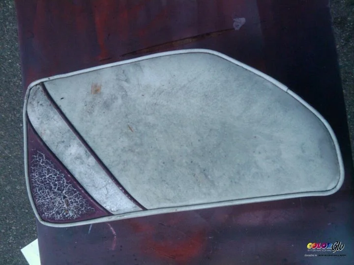 A vintage side mirror with a rusted frame and weathered reflective surface, resting on a dark surface.