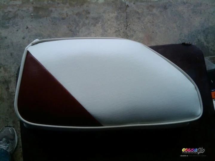 A motorcycle side mirror with a red, white, and black color scheme, positioned on a surface with a concrete background.