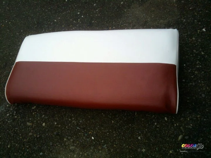 A padded, rectangular object with white and brown sections, lying on a dark, gravelly surface.