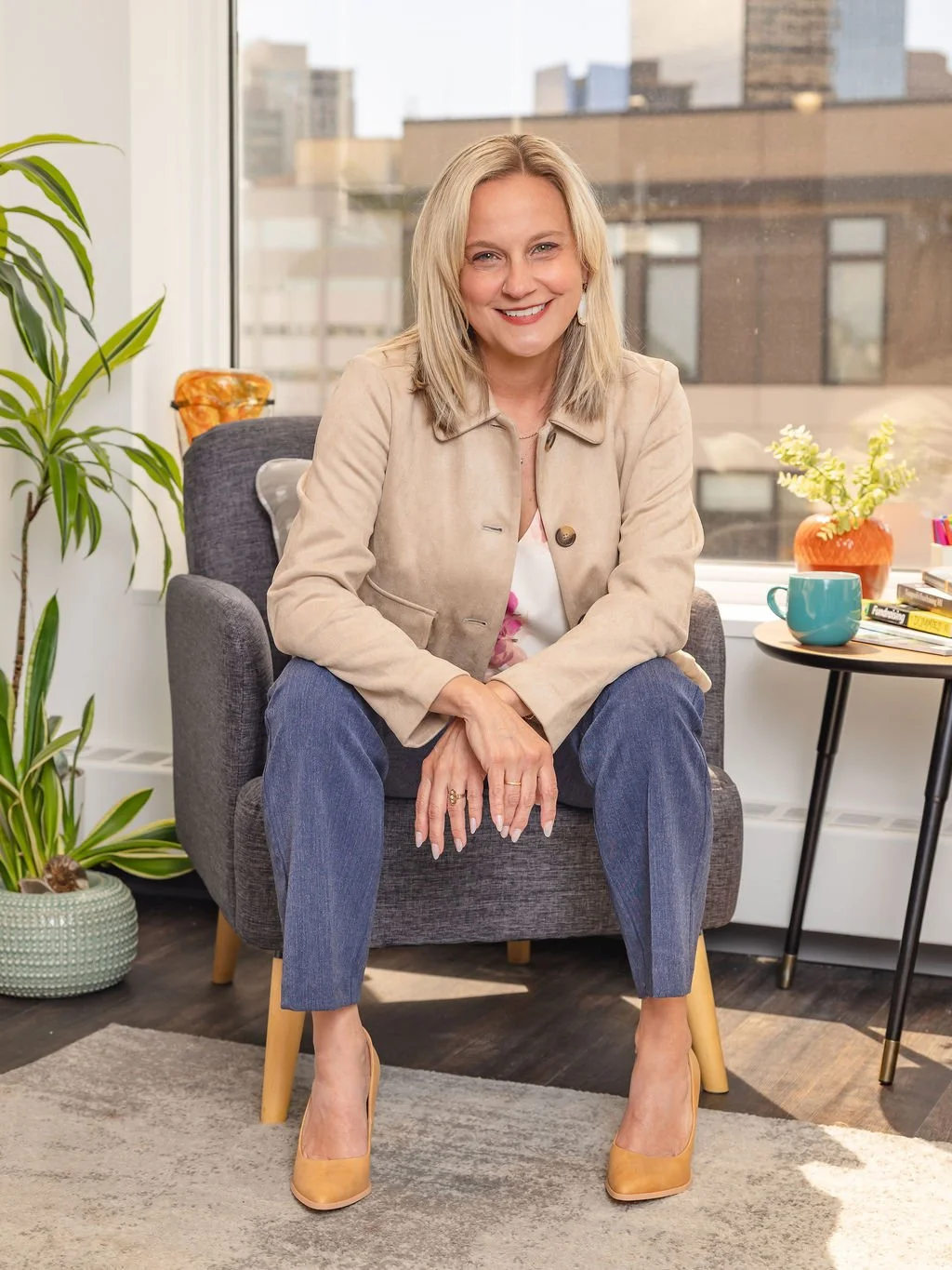 Brittny Wilson, Founder of Rooted Hire sitting on a grey chair in an office setting