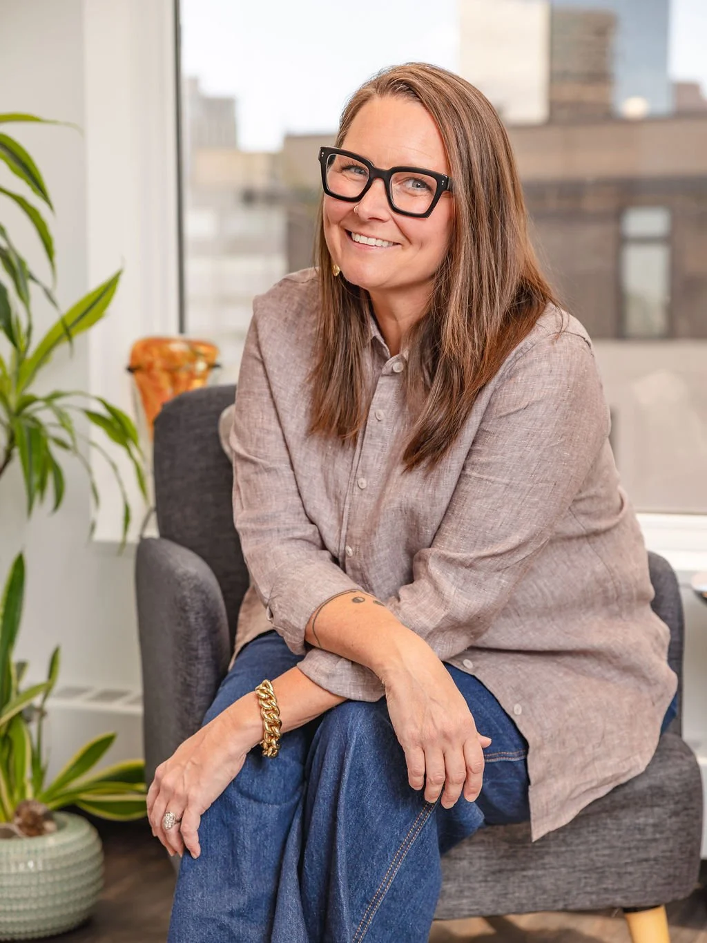 Courtney Schwartz, Recruitment specialist at Rooted Hire smiling sitting on a chair