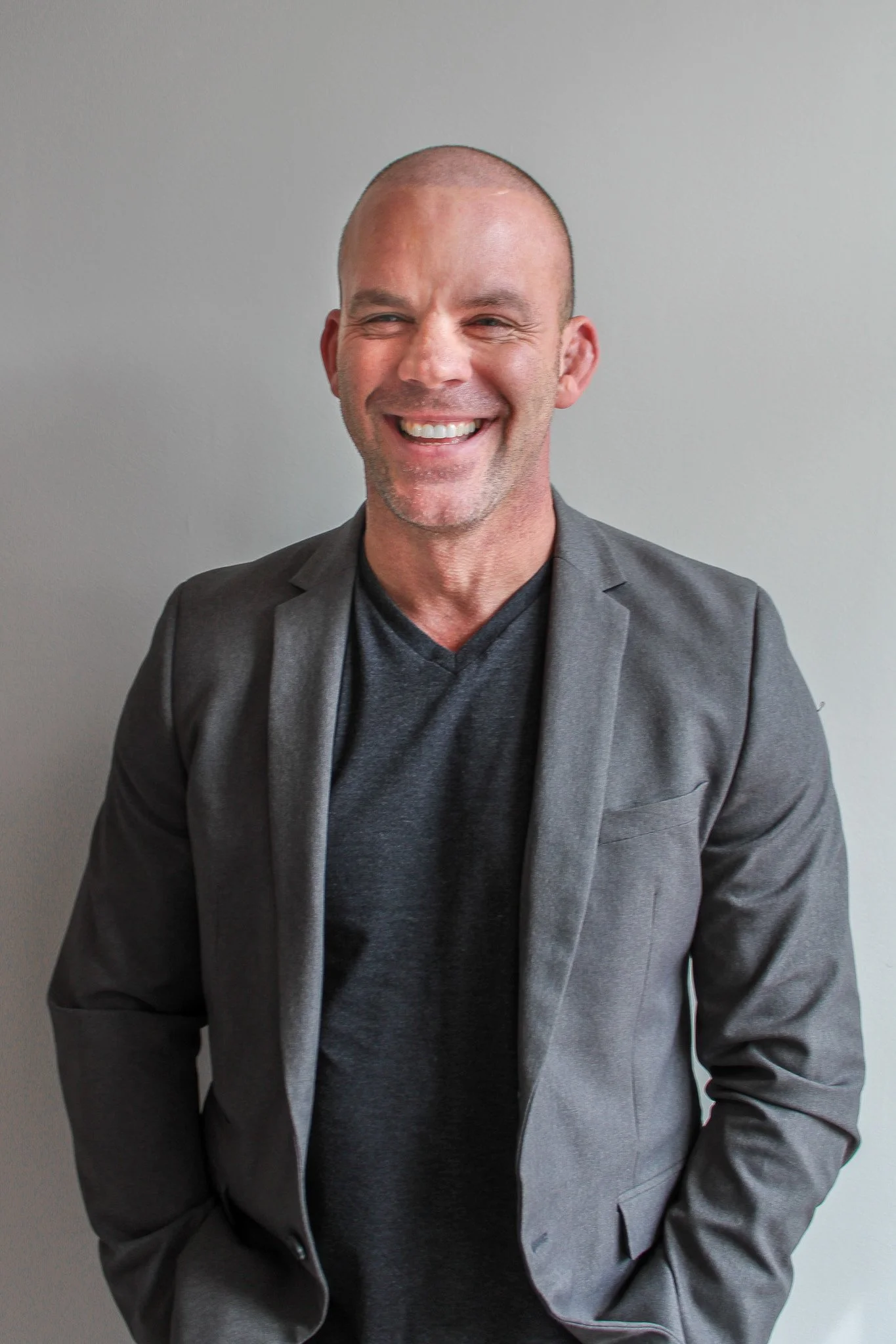 Tim Stout, owner of Tim Stout Group smiling wearing a gray blazer and dark shirt against a plain background.