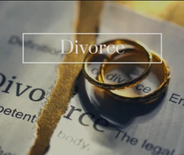 Two gold wedding rings resting on a torn page of a newspaper that reads 'Divorce'.