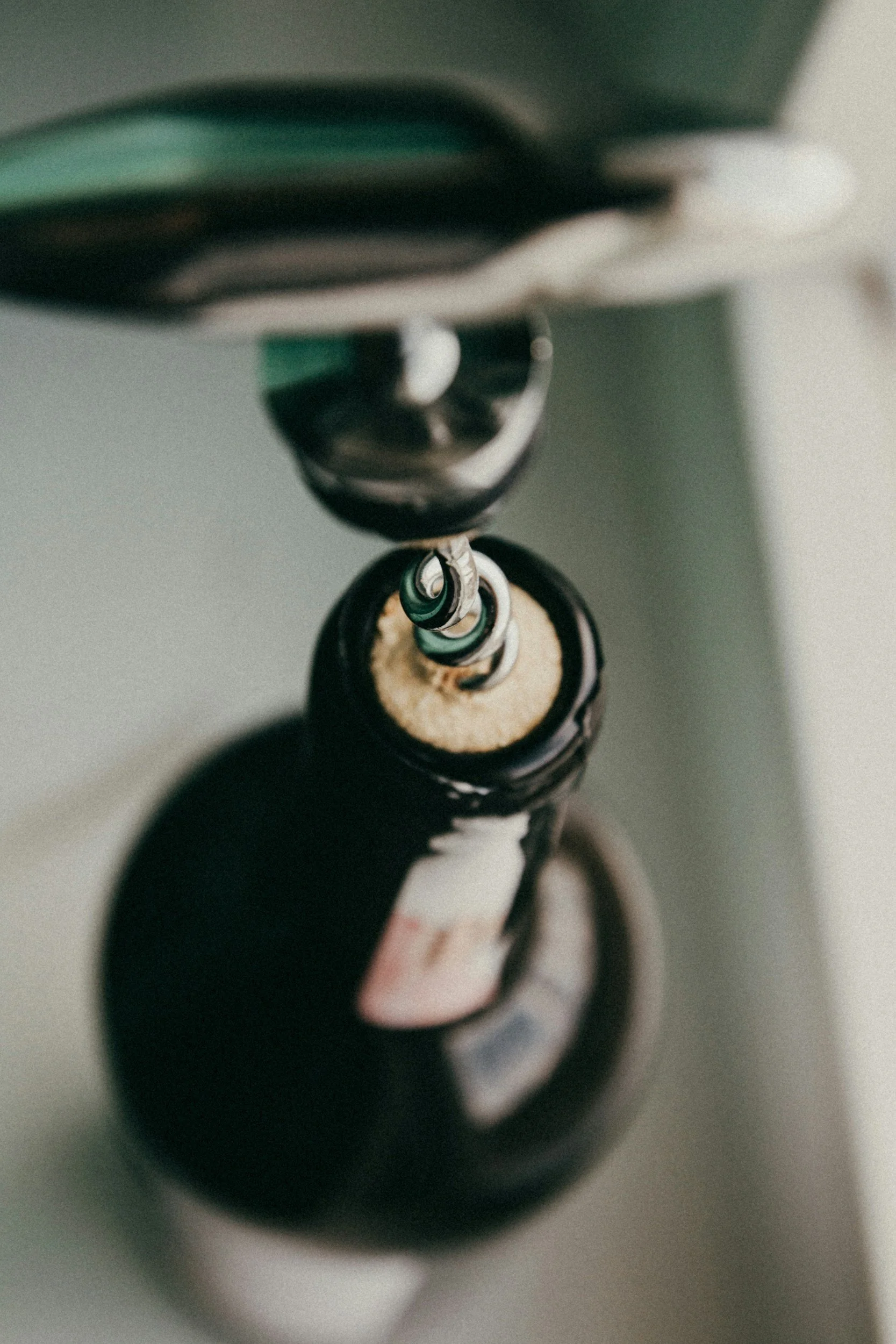 Close-up of a corkscrew twisting into a wine bottle, viewed from above.