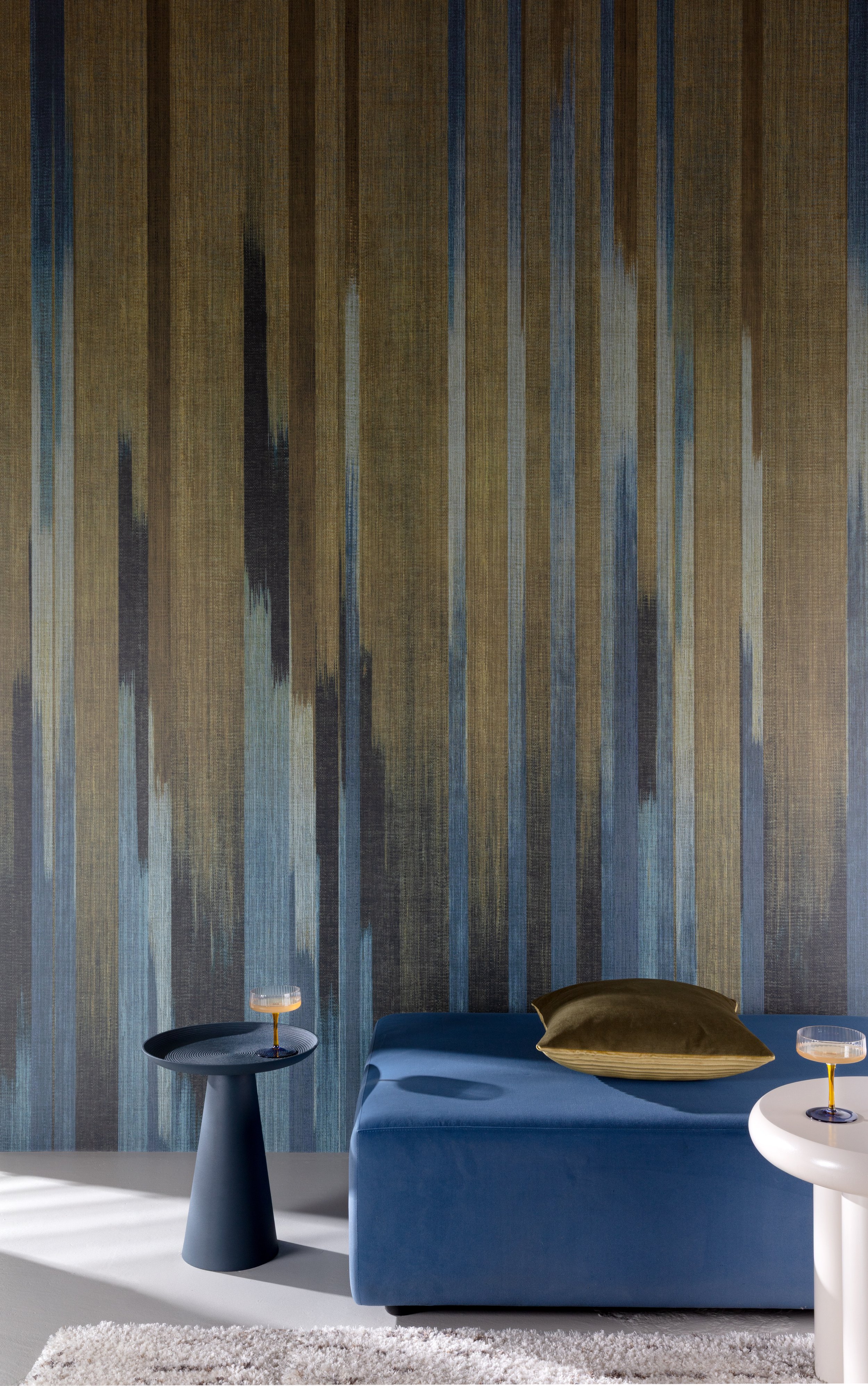 Kleurrijke woonkamer met blauwe zetel, goudkleurig kussen en gestreept behang.