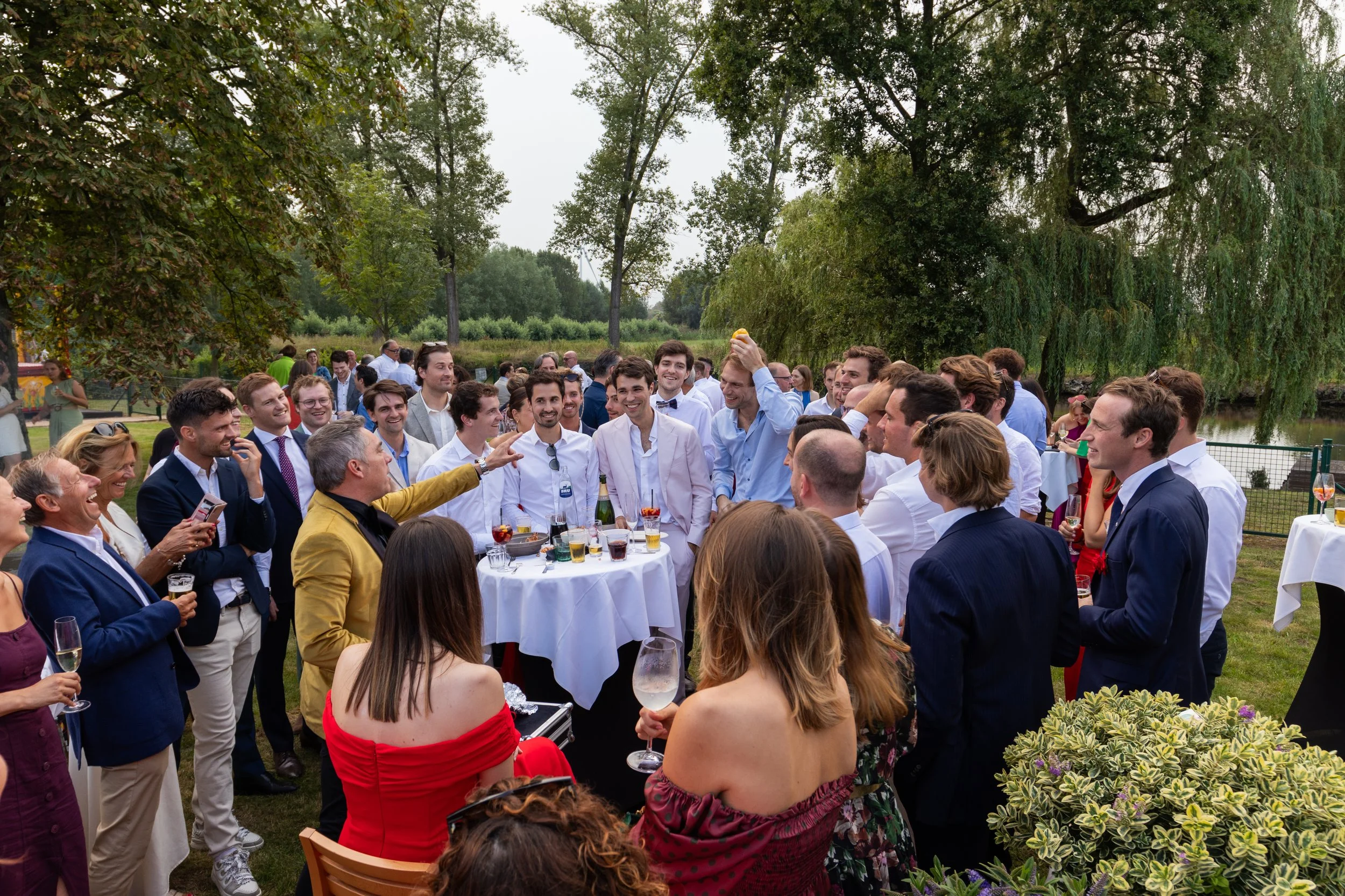 Gasten genieten aan gedekte tafels van een sfeervol familiefeest aan het water.