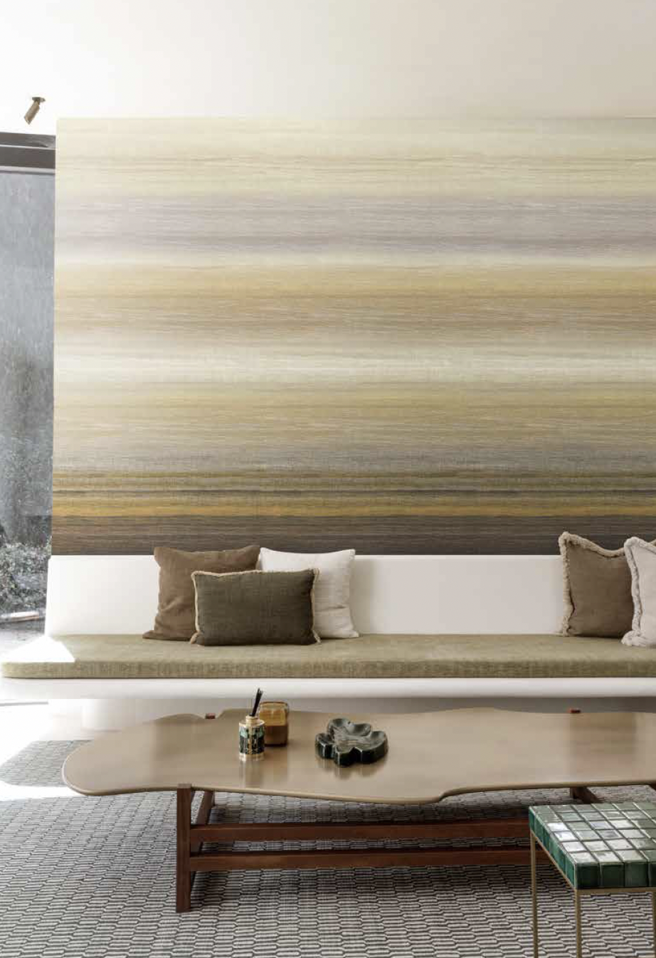 Sfeervolle woonkamer met beige zetel, groot abstract schilderij, houten salontafel en patroonvloerkleed.