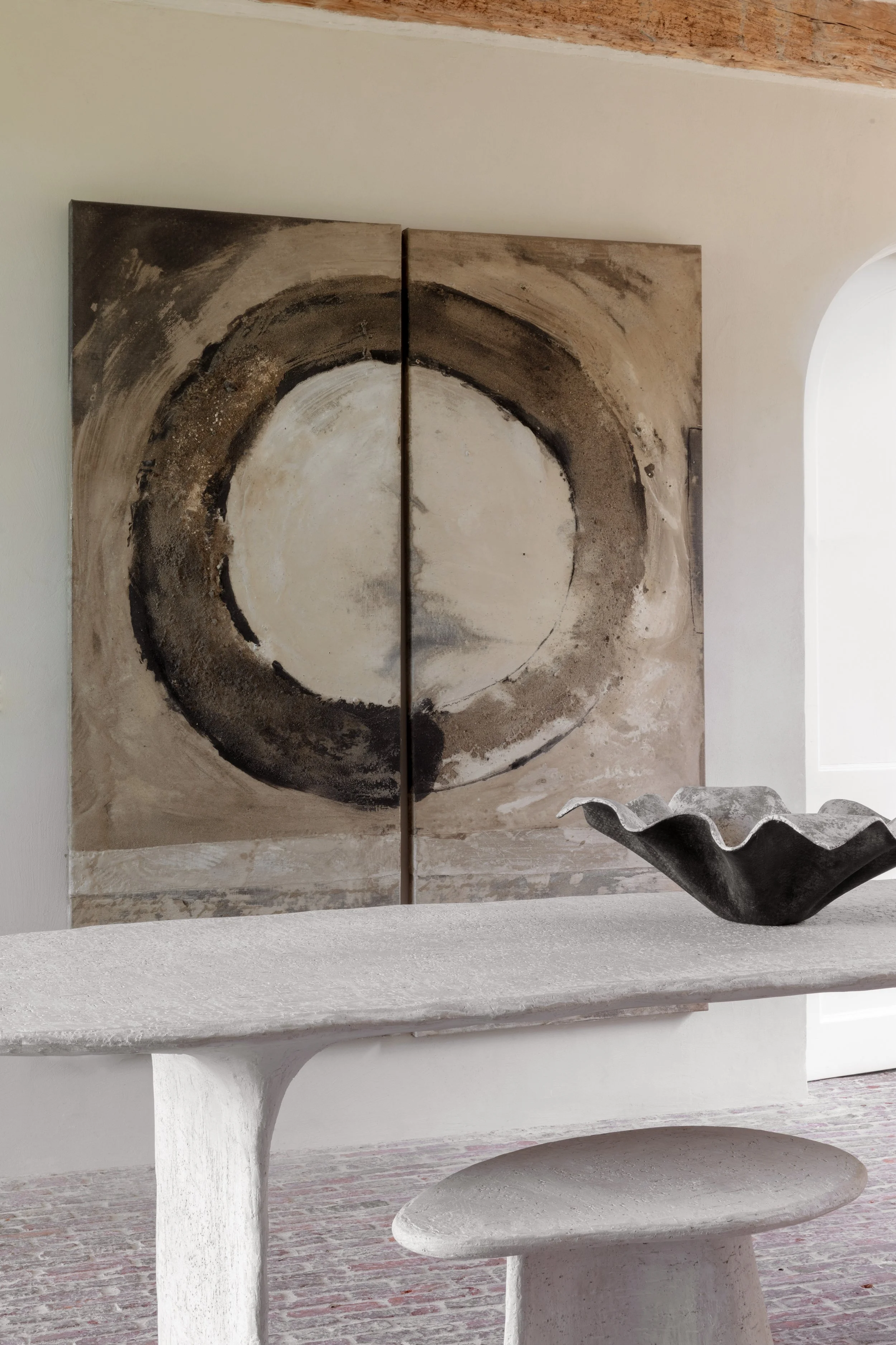 Minimalistisch interieur met groot abstract kunstwerk in warme aardetinten.