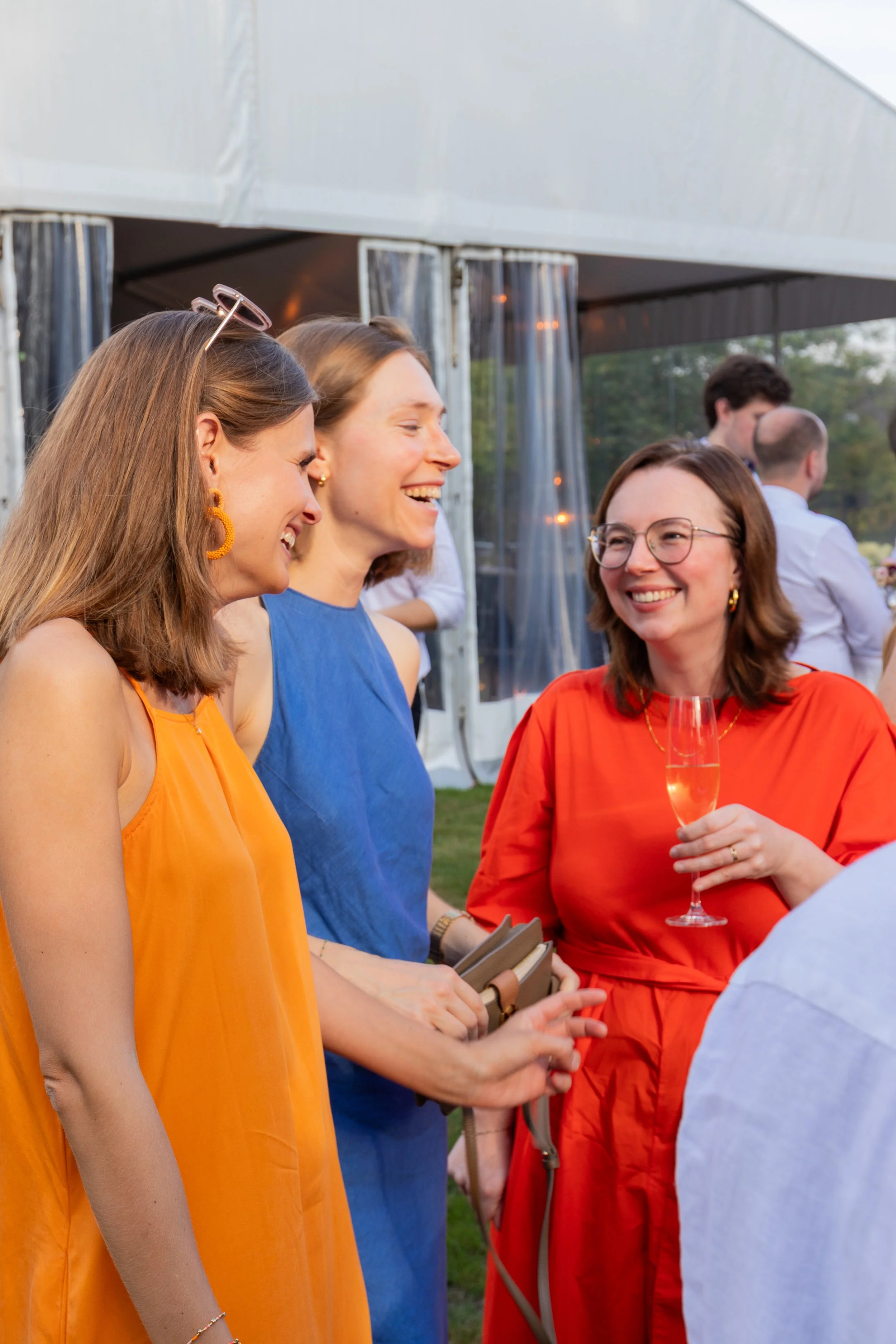 Drie vrouwen in kleurrijke jurken genieten samen van een drankje op het familiefeest.