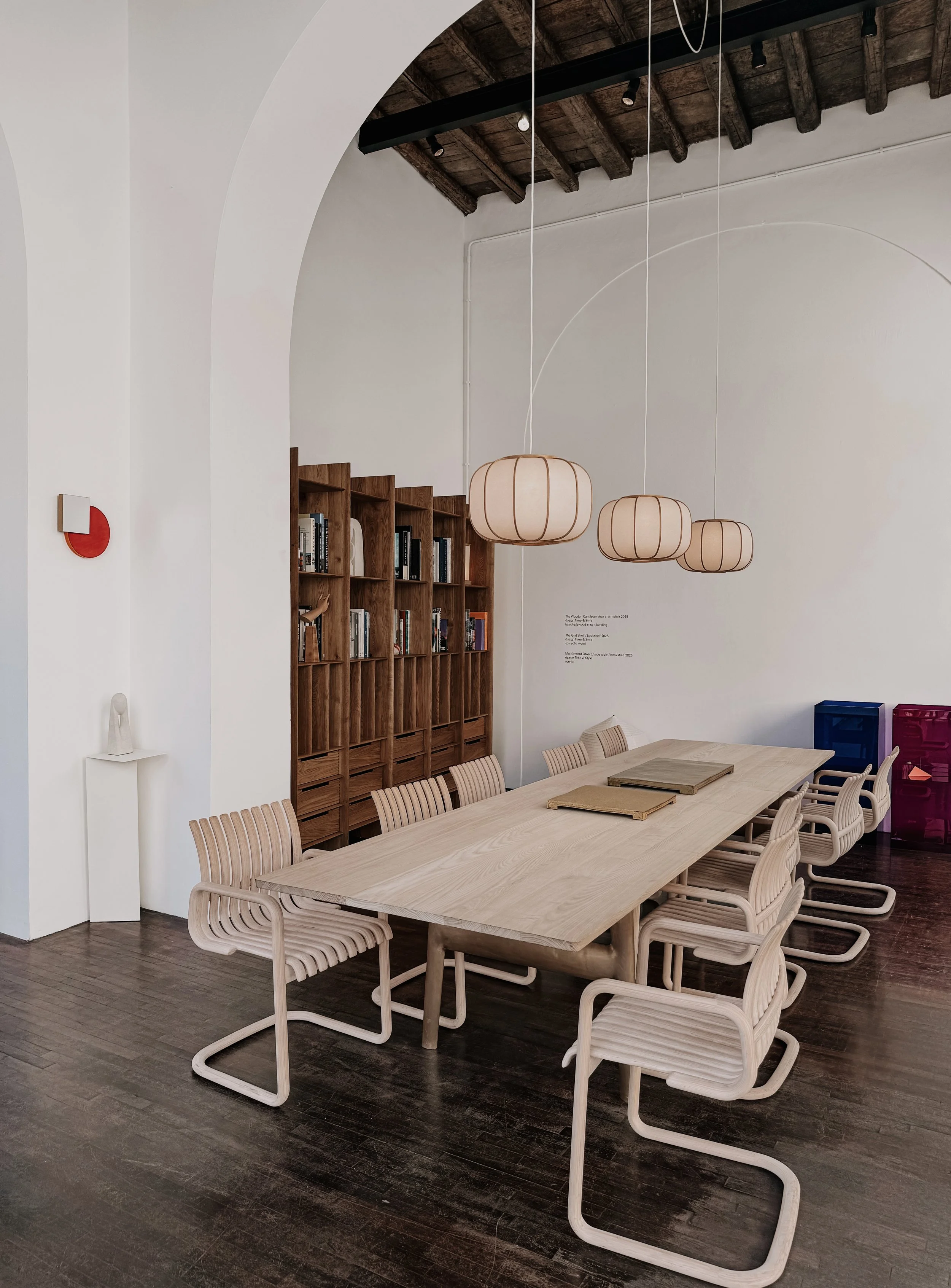 Ruime eetkamer met houten tafel en stoelen, ronde hanglampen en zichtbare houten plafondbalken.