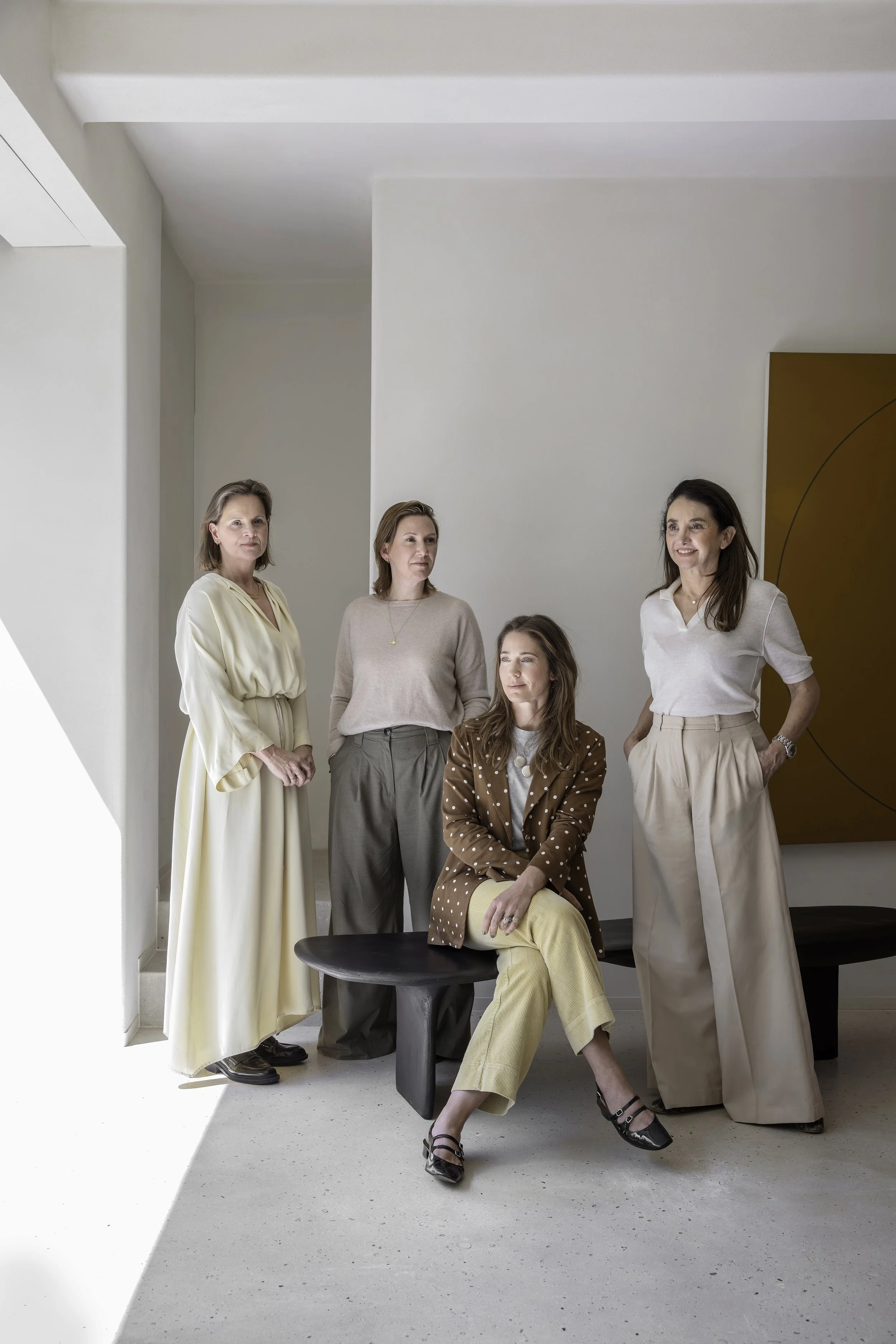 Professionele groepsfoto van vijf vrouwelijke interieurarchitecten in neutrale outfits in een modern interieur.