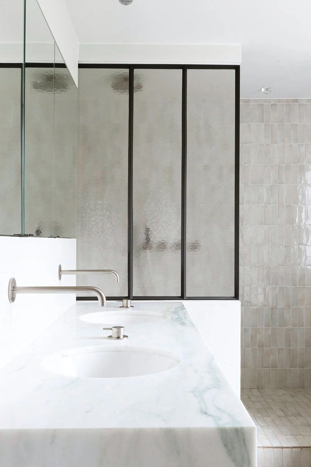 Professionele interieurfotografie van een moderne badkamer met dubbele wastafel in marmer en inloopdouche.