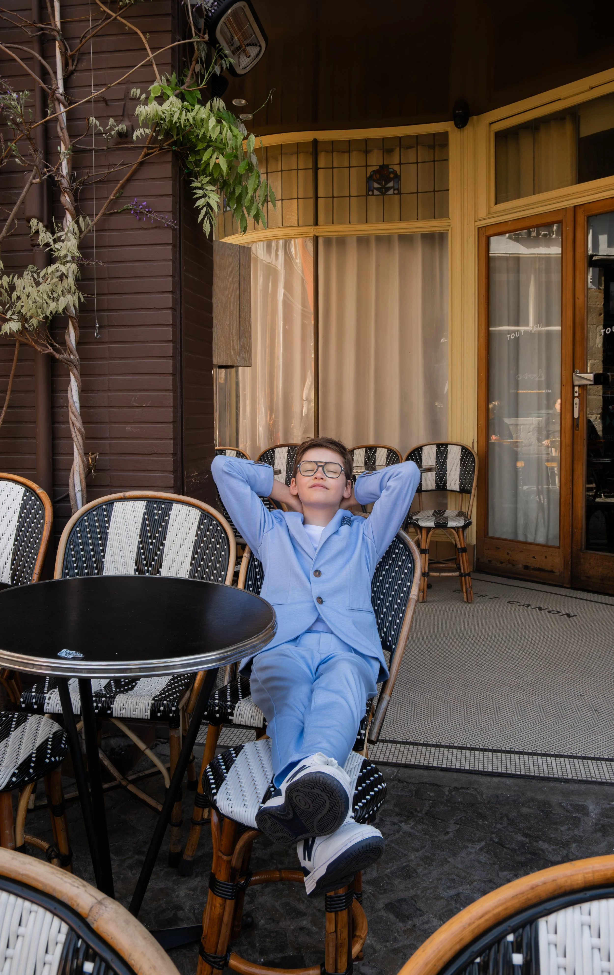 Jongen met bril en lichtblauw kostuum tijdens een communie shoot.