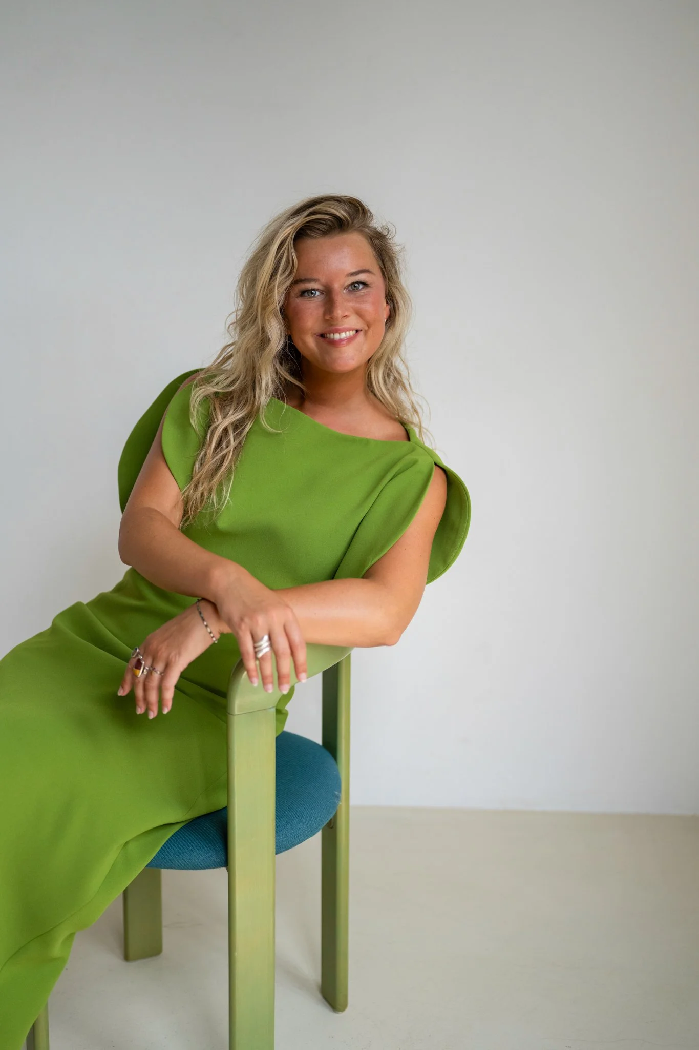 Professioneel brandingportret van een lachende onderneemster in een felgroene jurk.