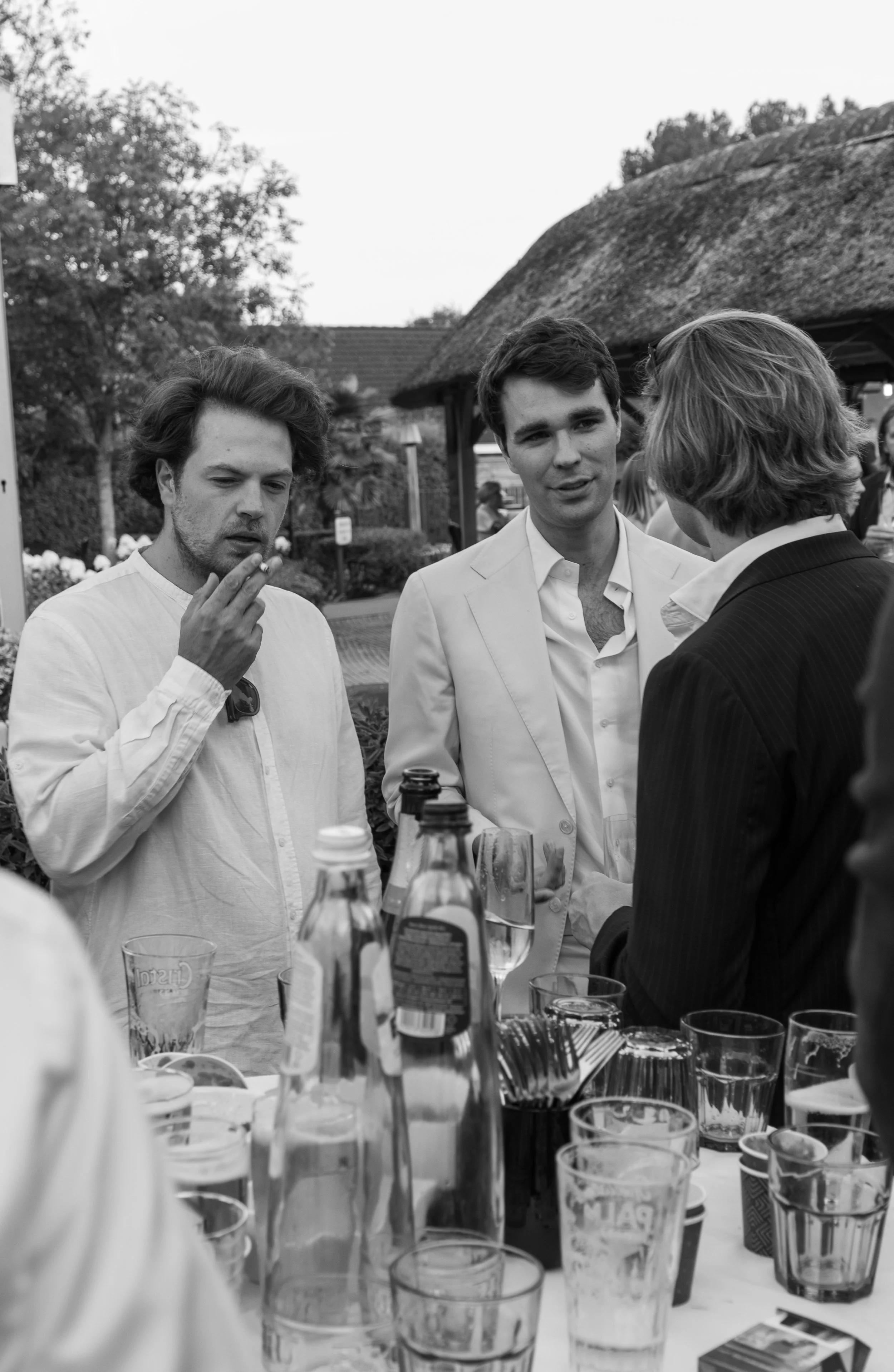 Drie mannen praten met elkaar aan een tafel tijdens een buitenevenement.