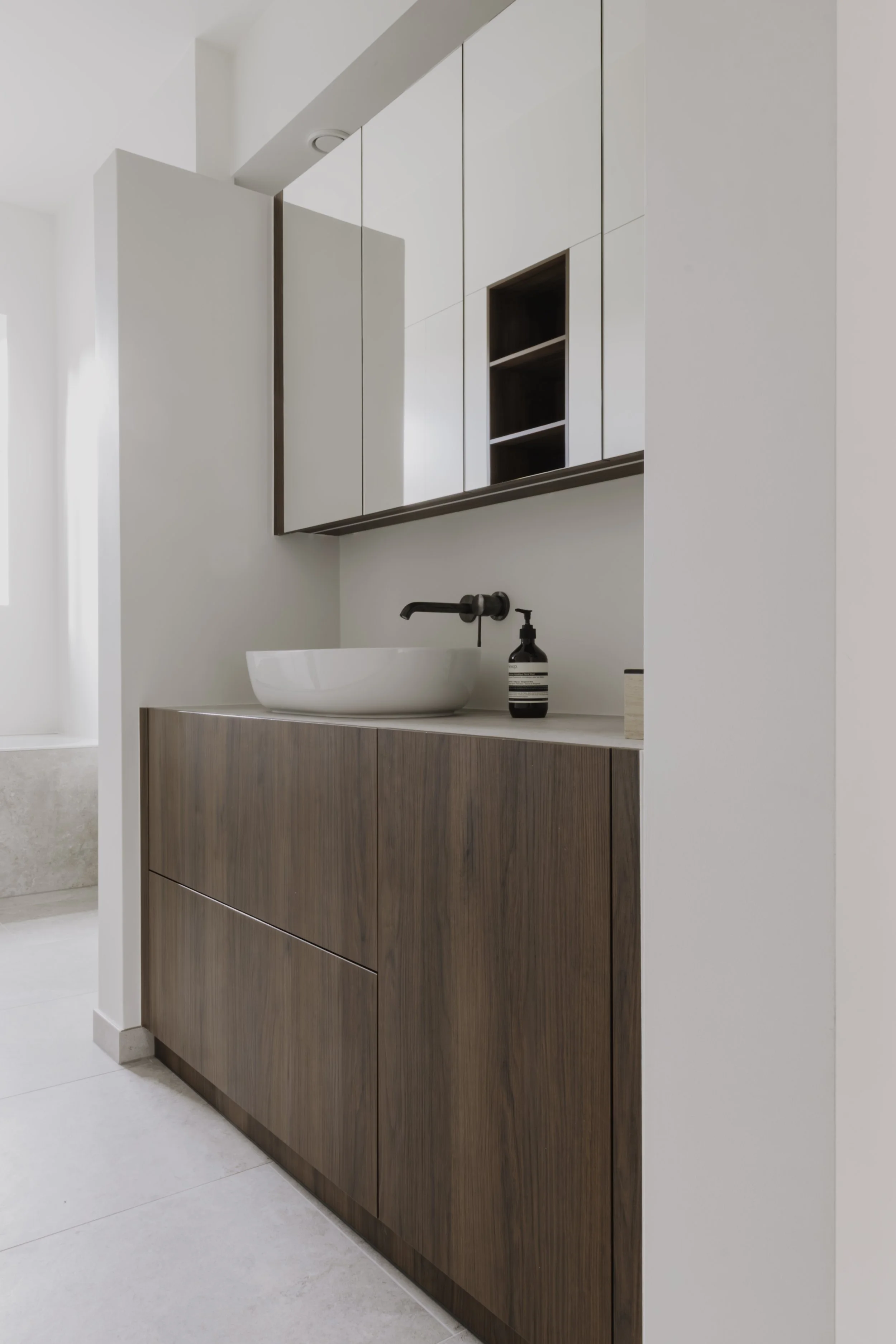 Moderne badkamer met witte waskom, zwarte kraan en houten badkamermeubel.