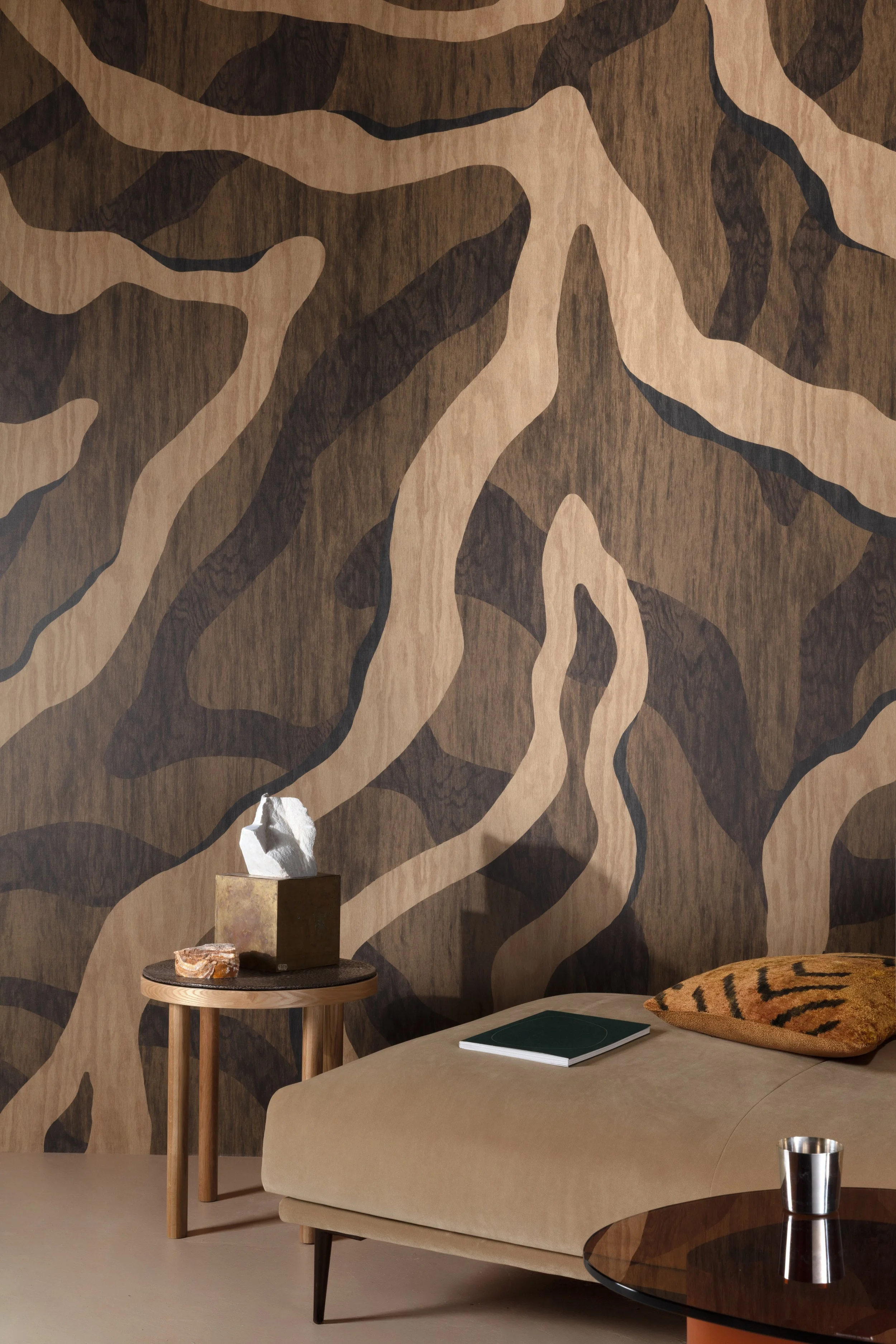Sfeervol interieur met een beige zetel, donkere accenten en een opvallende abstracte wand.