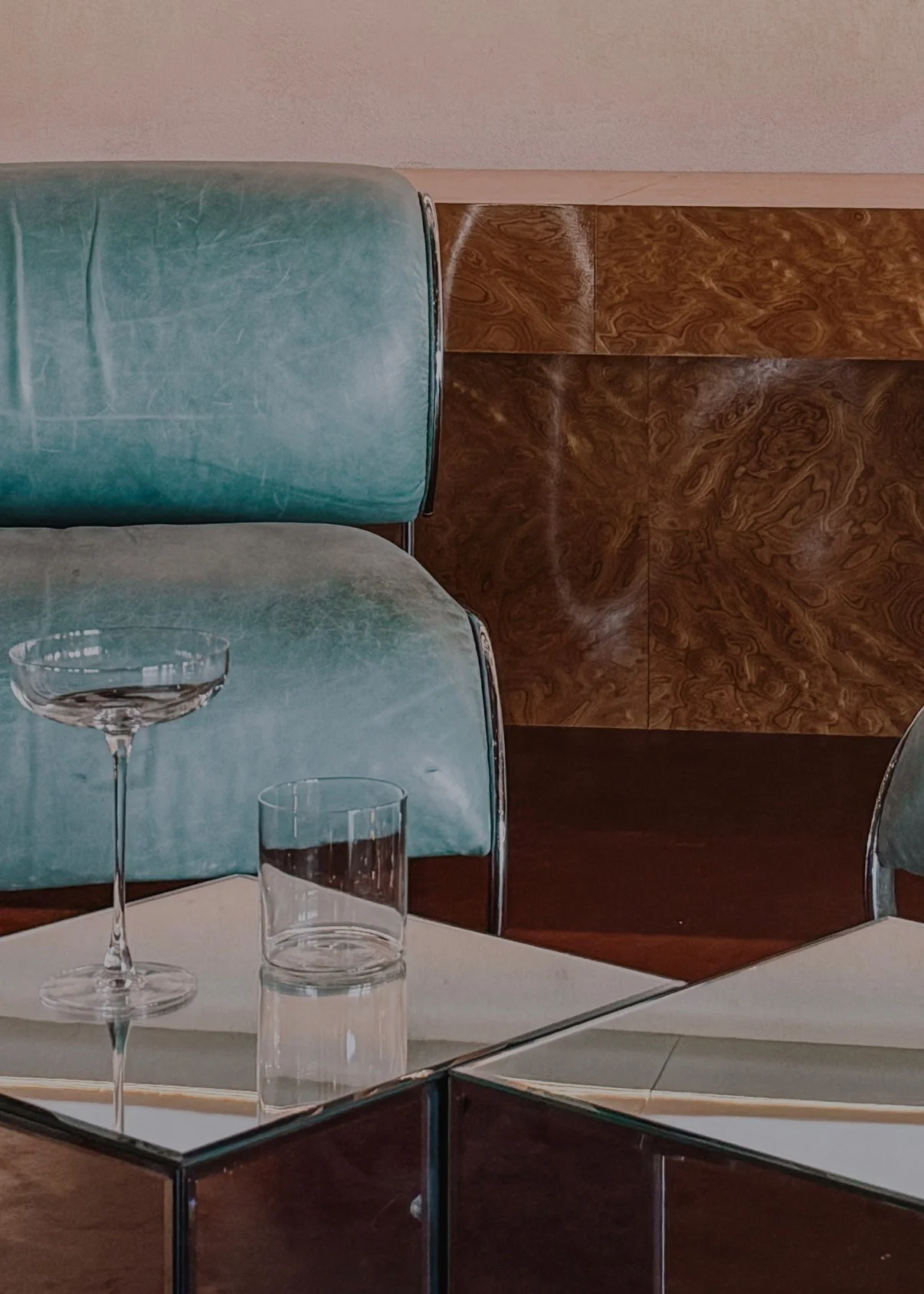 Interieurdetail met vintage turquoise zetel, houten wand en witte tafel met glazen.