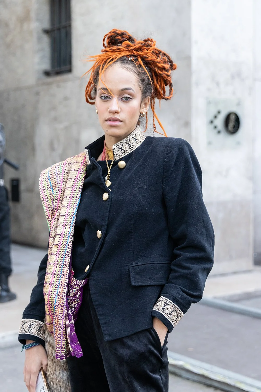 Creatief straatportret van een vrouw met rode dreadlocks en een stijlvolle zwarte jas.
