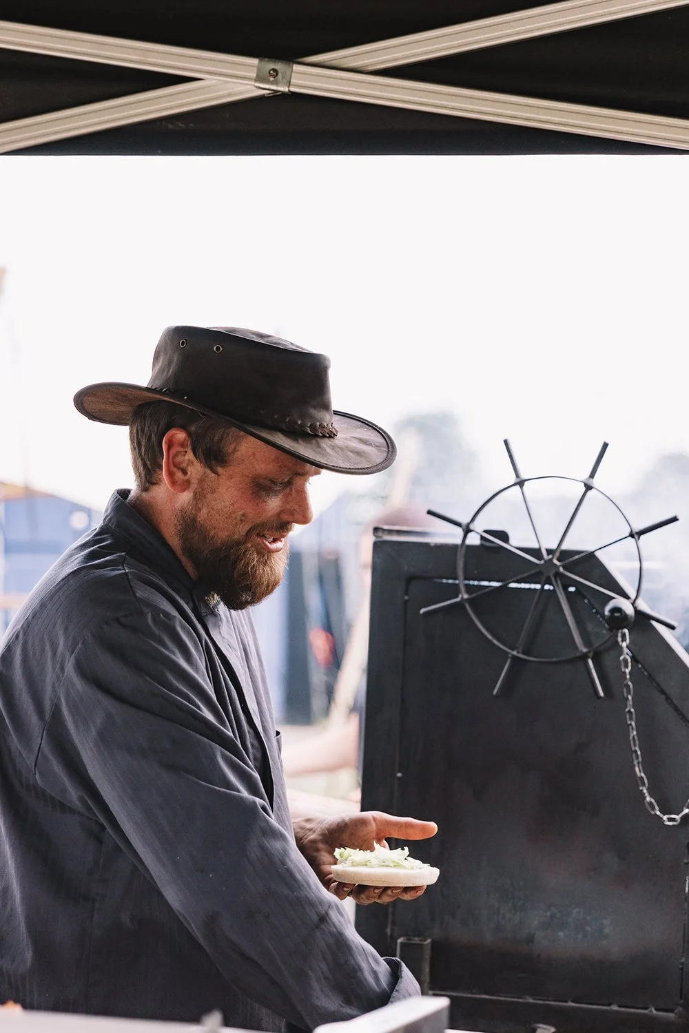 Man met cowboyhoed geniet van streetfood tijdens een evenement in openlucht.