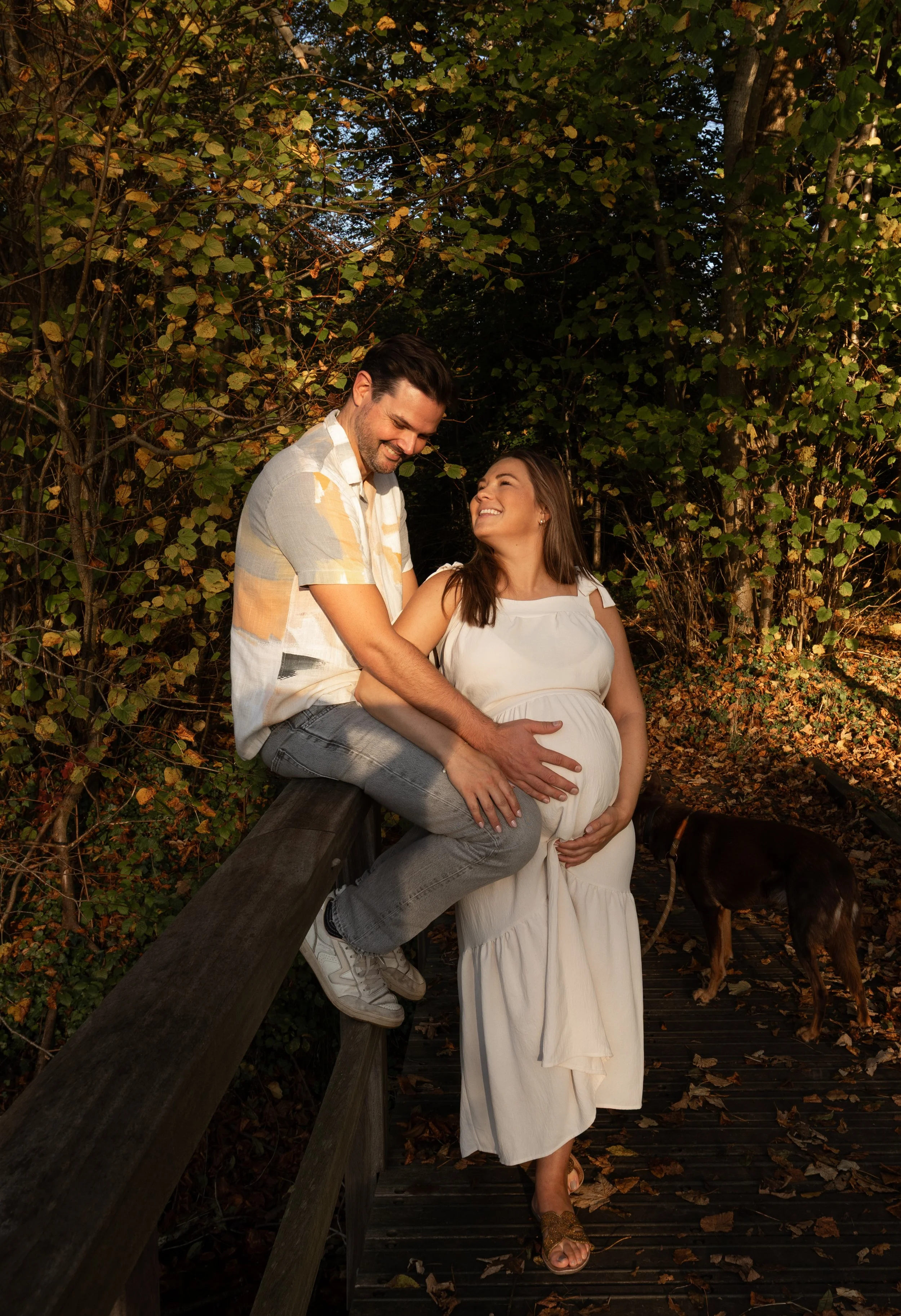 Spontane zwangerschapsfoto van een aanstaand ouderpaar tijdens een liefdevol moment in de natuur.