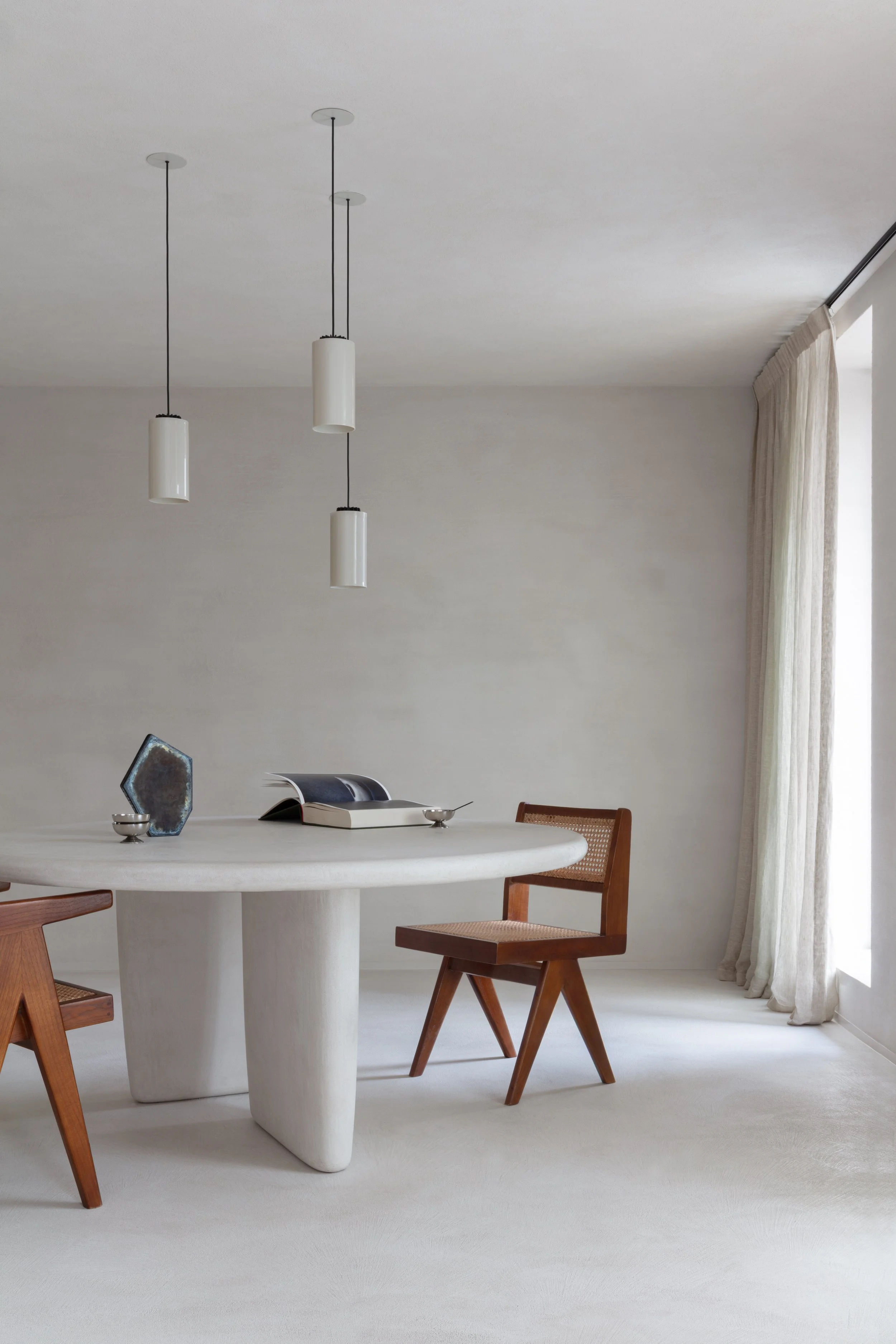 Professionele interieur fotografie van een minimalistische eetruimte met een ronde tafel en houten stoelen.
