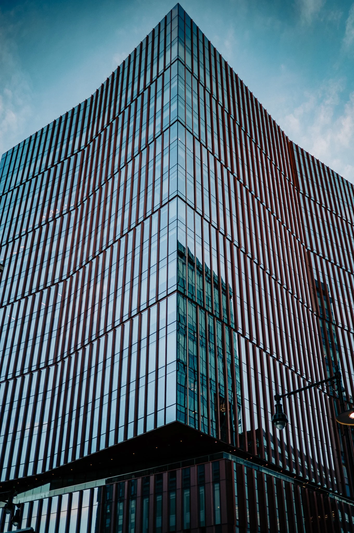 A modern glass building rises against a blue sky, its facade reflected in crisp vertical lines.