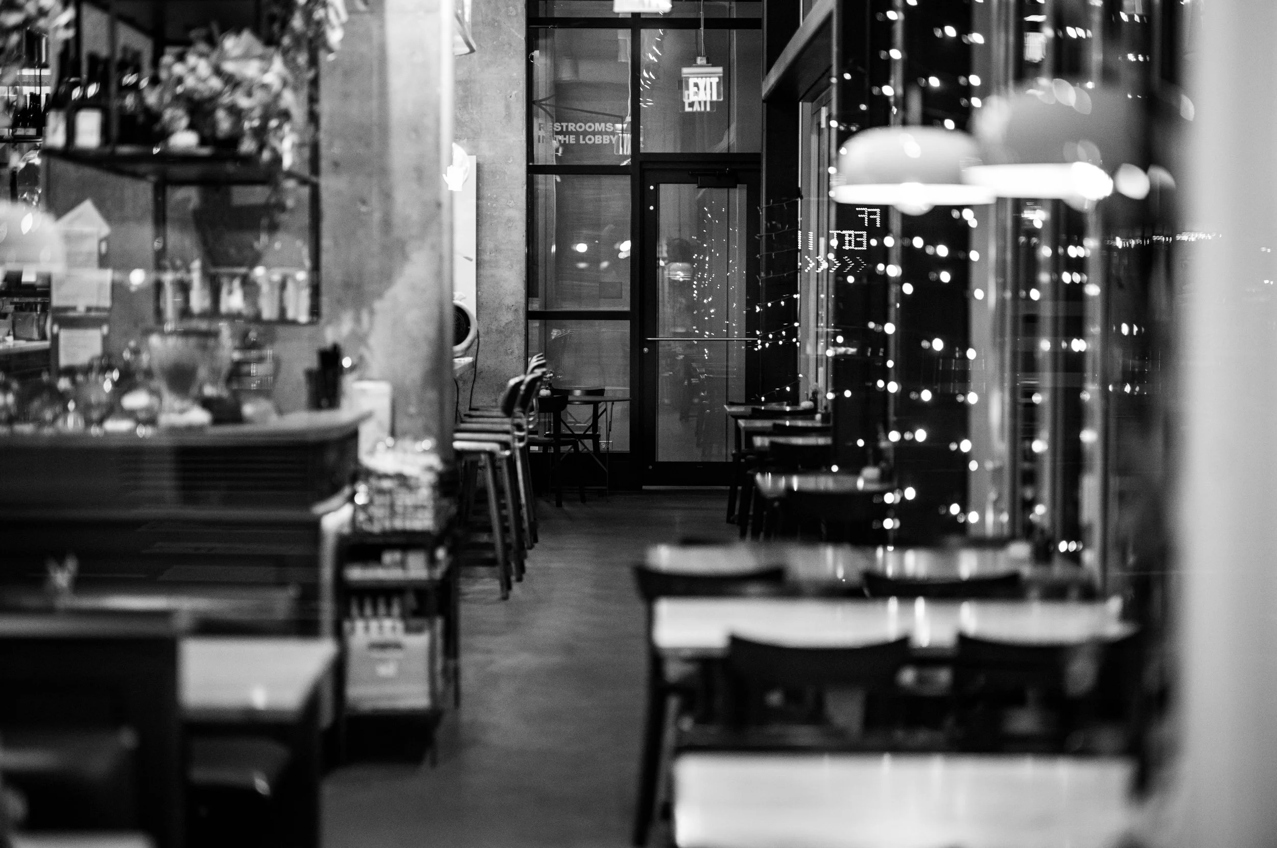 Rows of tables and pendant lights lead into a softly focused cafe interior.